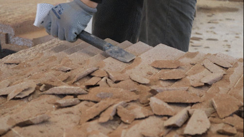 Person breaking sandstone into smaller pieces at a construction site.