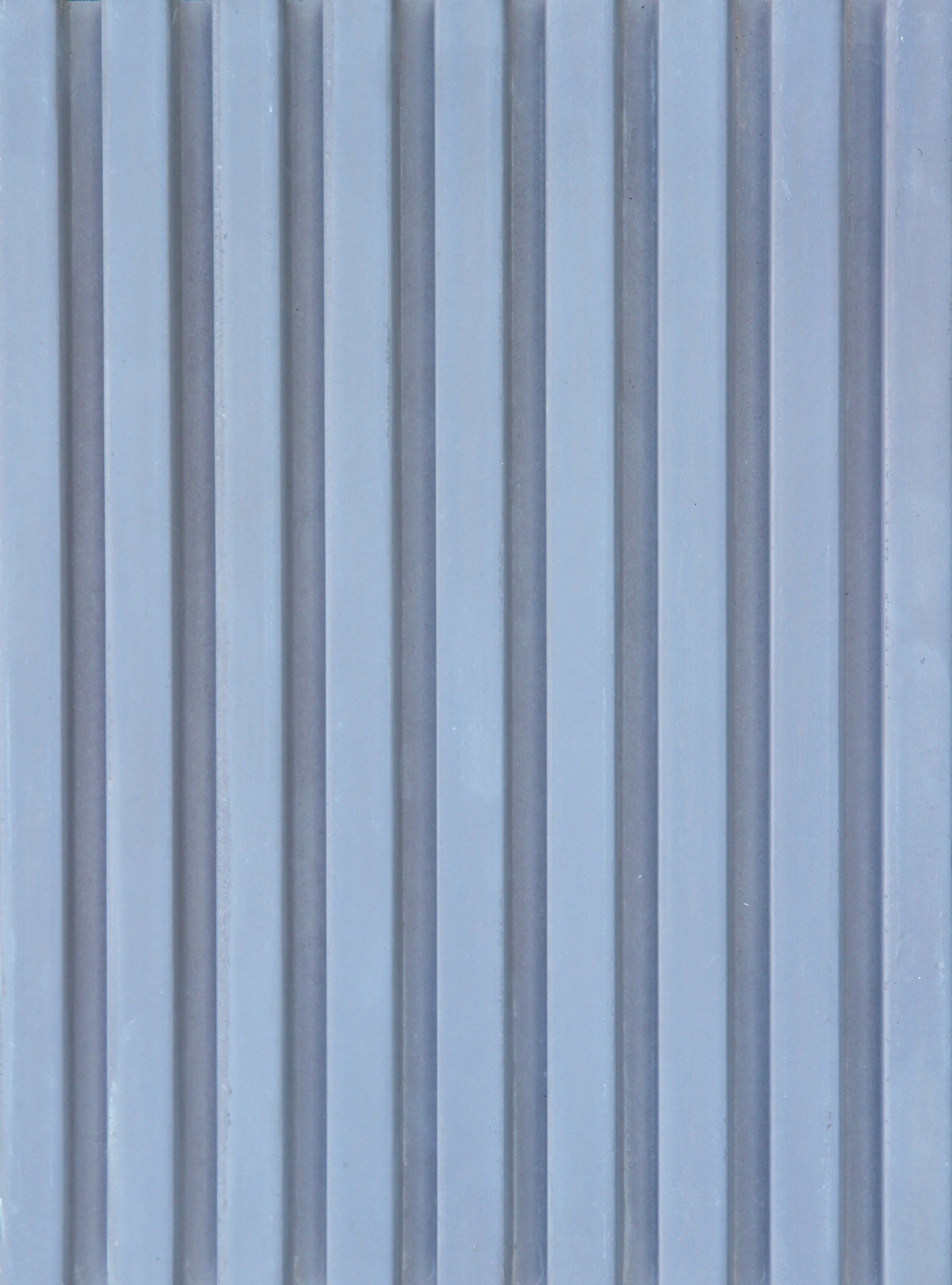 Close-up of a metallic wall with vertical ridges, painted in a light blue color.