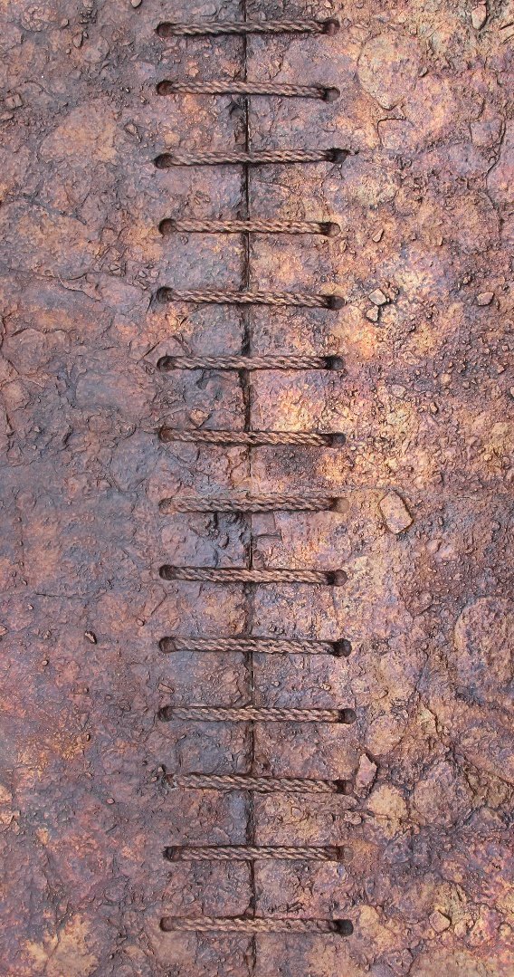 Close-up of a rusty metal ladder embedded in cracked, weathered dirt or rock ground.