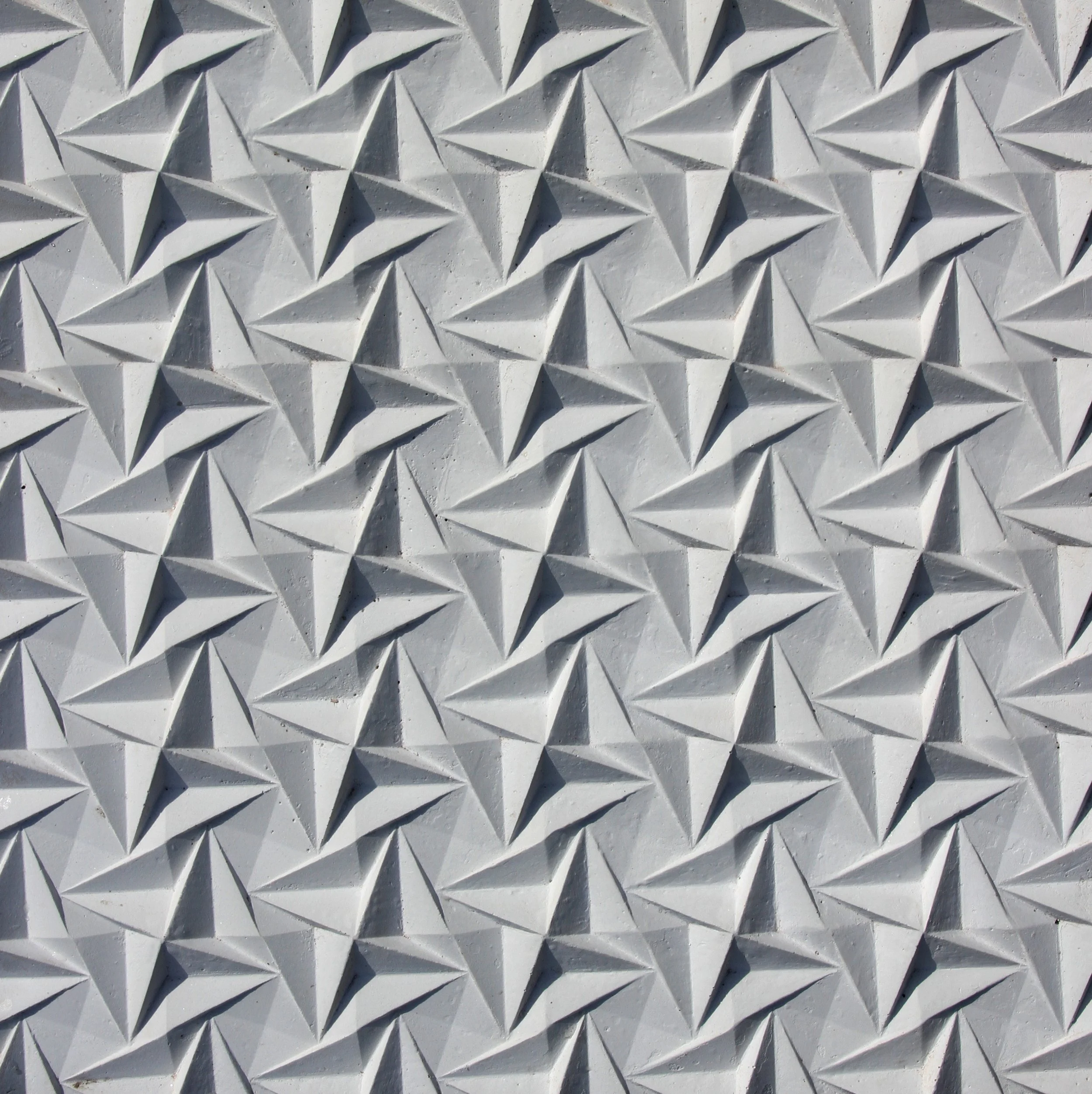 Close-up of a textured wall with a repeating geometric pattern of diamond shapes creating a three-dimensional effect.