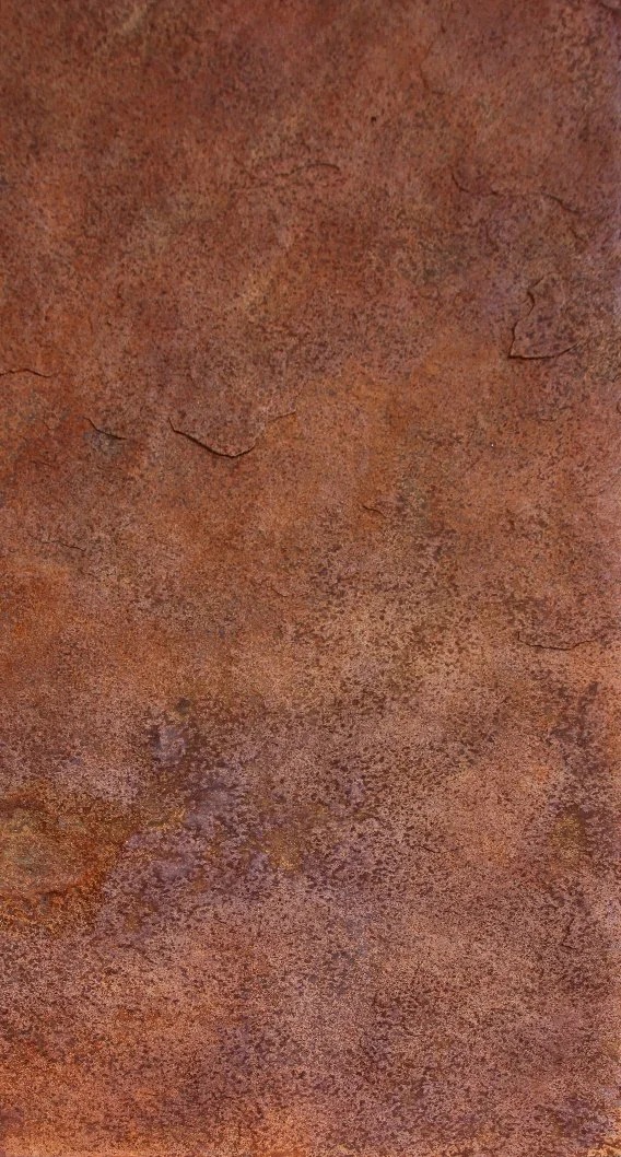 Close-up of a rusty metal surface with reddish-brown coloration and textured cracks.