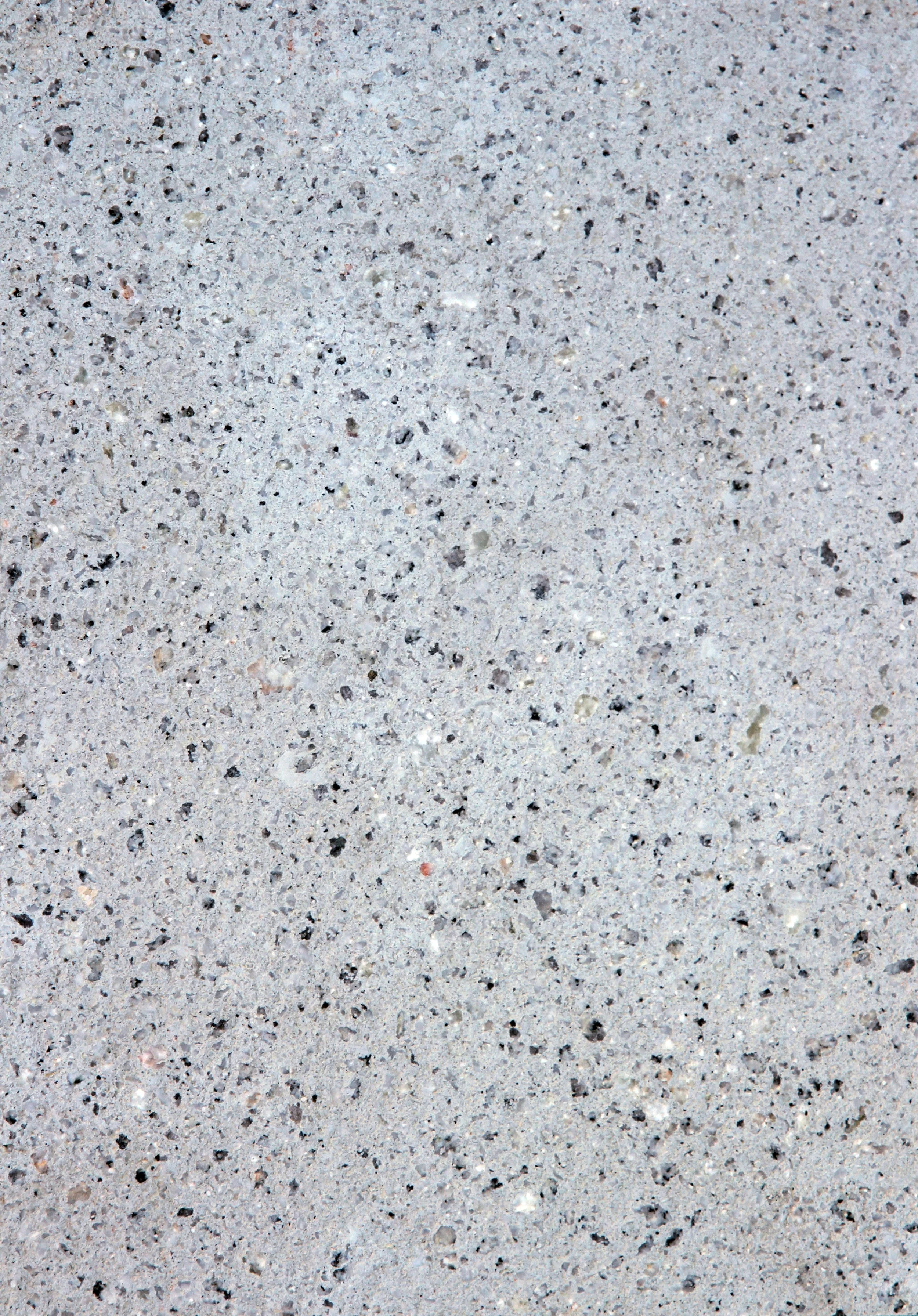 Close-up view of a speckled concrete surface with small chips and particles of various colors.