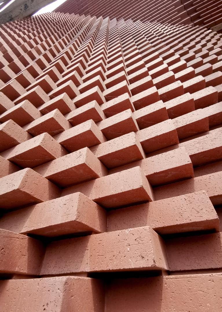 Close-up of a textured brick wall with protruding bricks arranged in a repeating pattern.