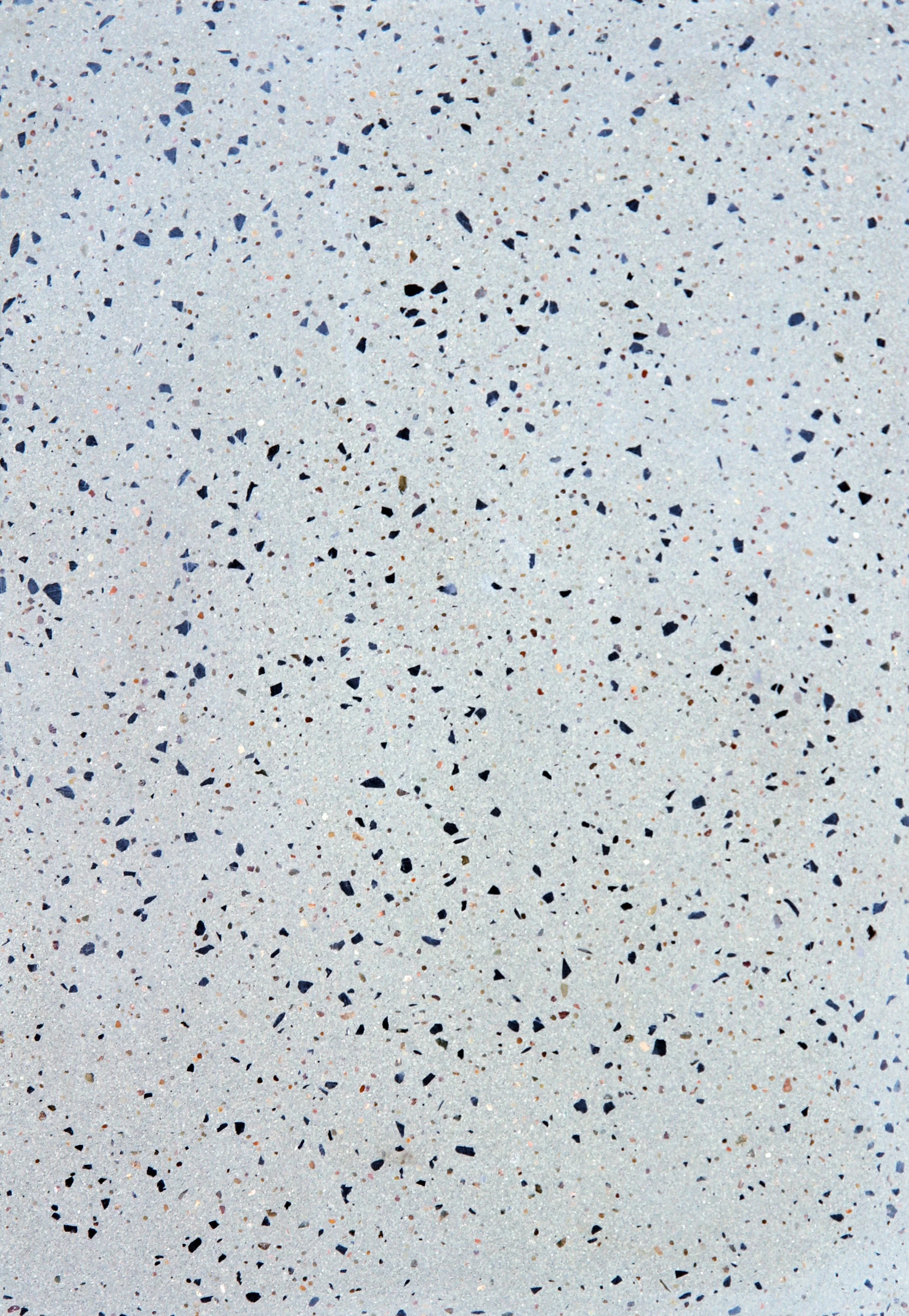 Close-up of a speckled grey terrazzo surface with small black, white, and brown fragments.