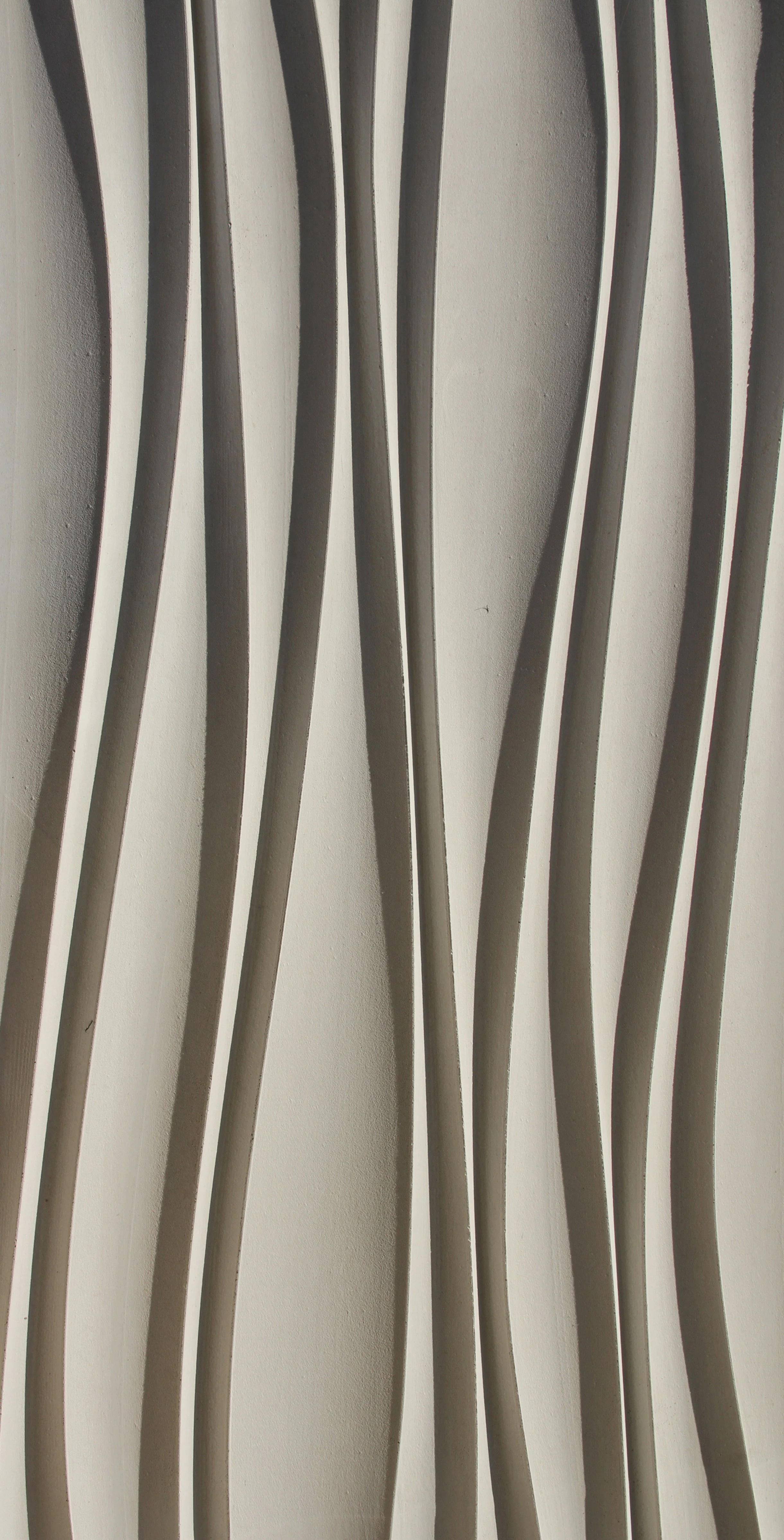 Close-up view of a modern decorative wall sculpture with elongated, curved, white slats arranged in an abstract pattern against a plain wall.
