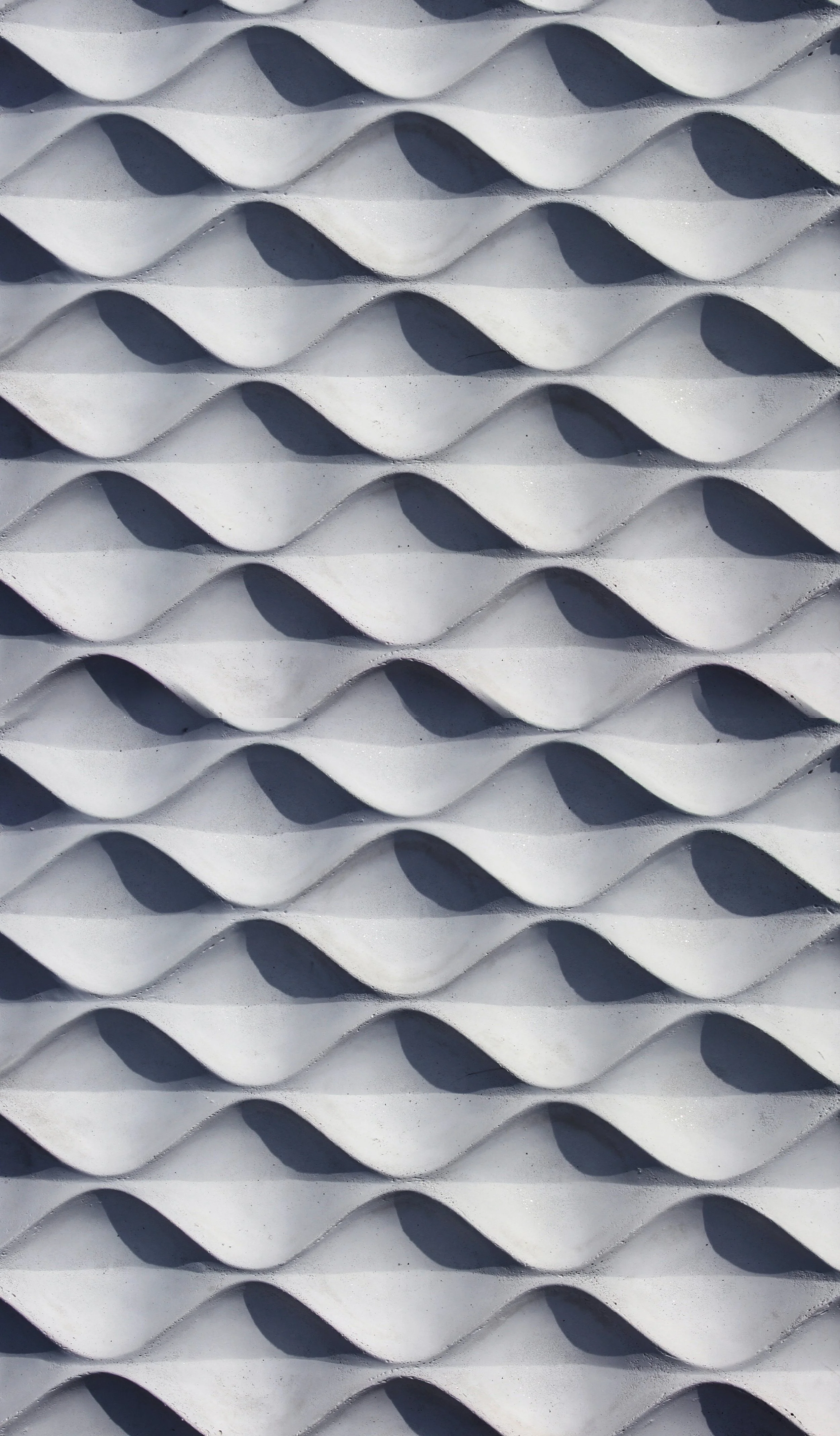 Close-up of a white, textured, wavy surface with shadows creating an illusion of depth and curves.