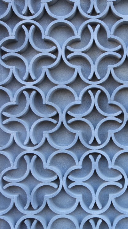 Close-up of a decorative concrete wall with a repeating geometric pattern of interlocking circles and curved shapes.