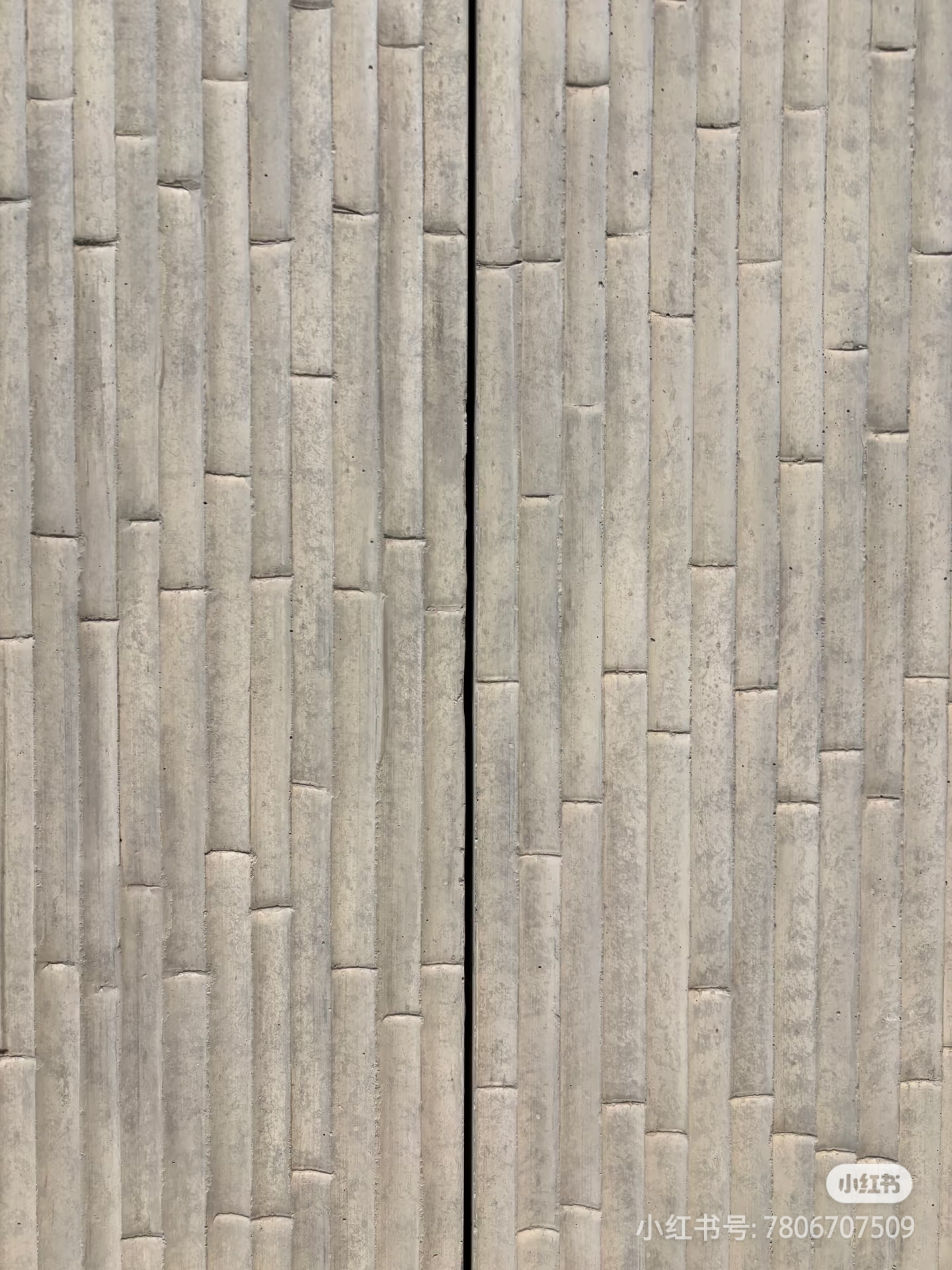 A close-up image of a textured concrete wall with vertical ridges and a narrow black gap in the middle.