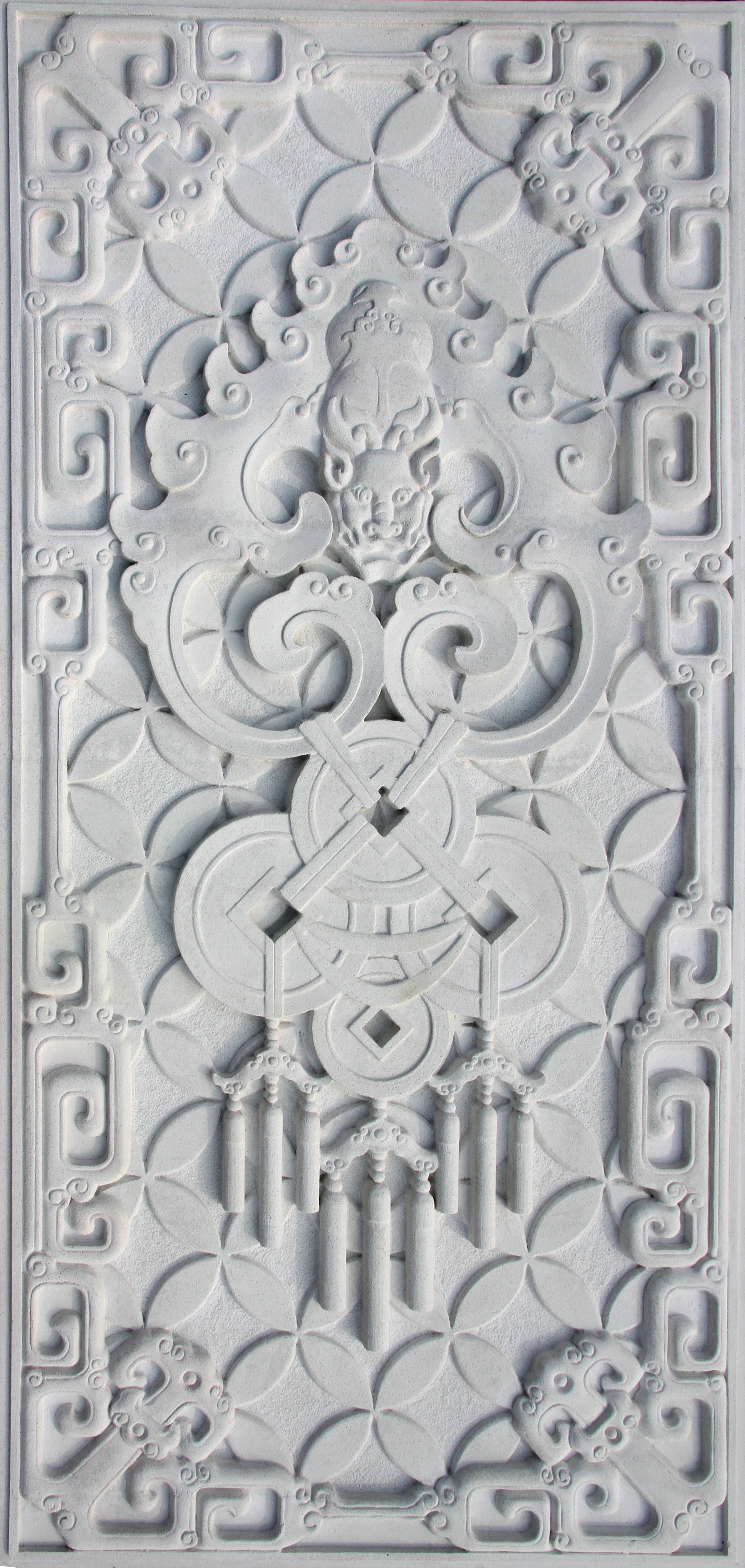 White carved decorative panel featuring a lion face, swirling patterns, circular motifs, and geometric borders.