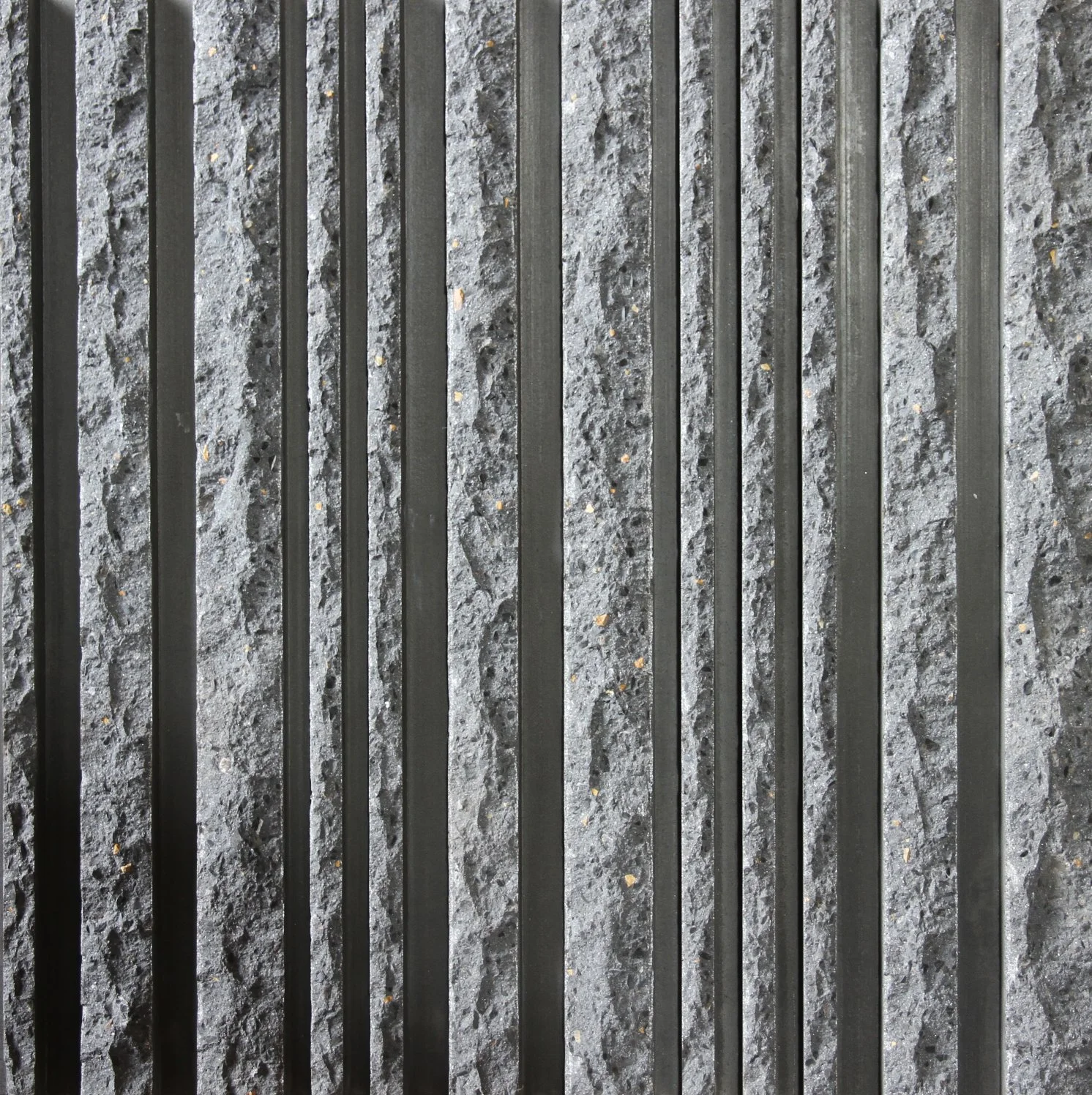 Close-up of black metal bars on a textured gray concrete surface.