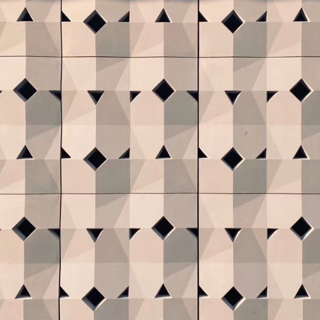 A wall with geometric 3D tiles featuring a pattern of squares and diamonds in shades of white and gray, with black square openings.