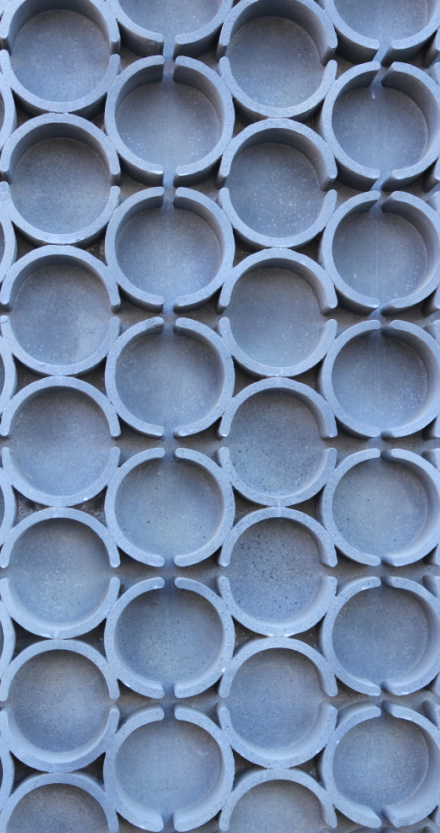 Close-up of multiple connected gray concrete or plastic pipes arranged in a repeating pattern.