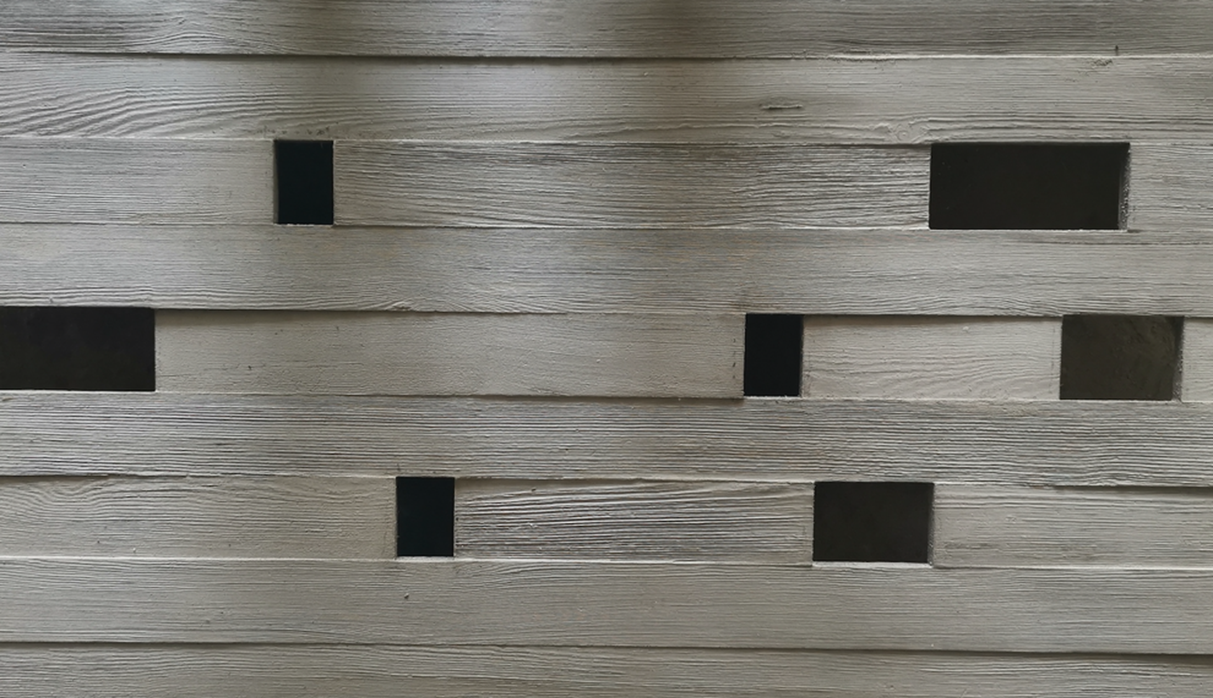 Close-up of a wooden fence with horizontal planks and rectangular cutouts.