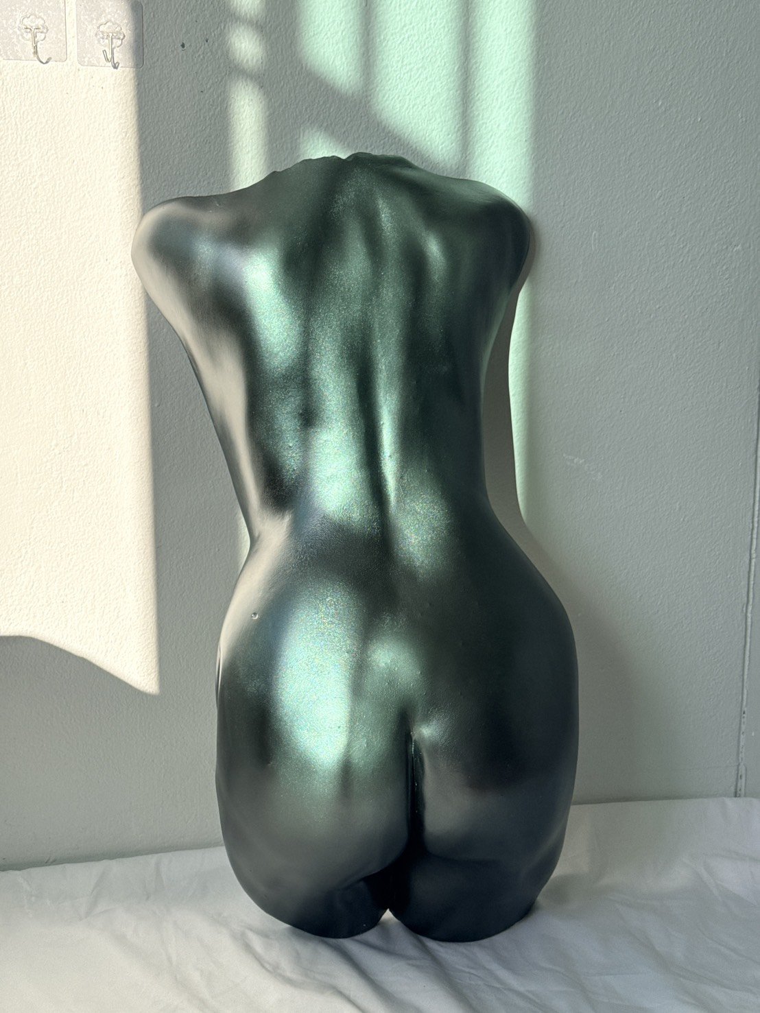 Standing bum cast body sculpture in dark teal metallic finish, rear view showing detailed back and buttocks torso art piece