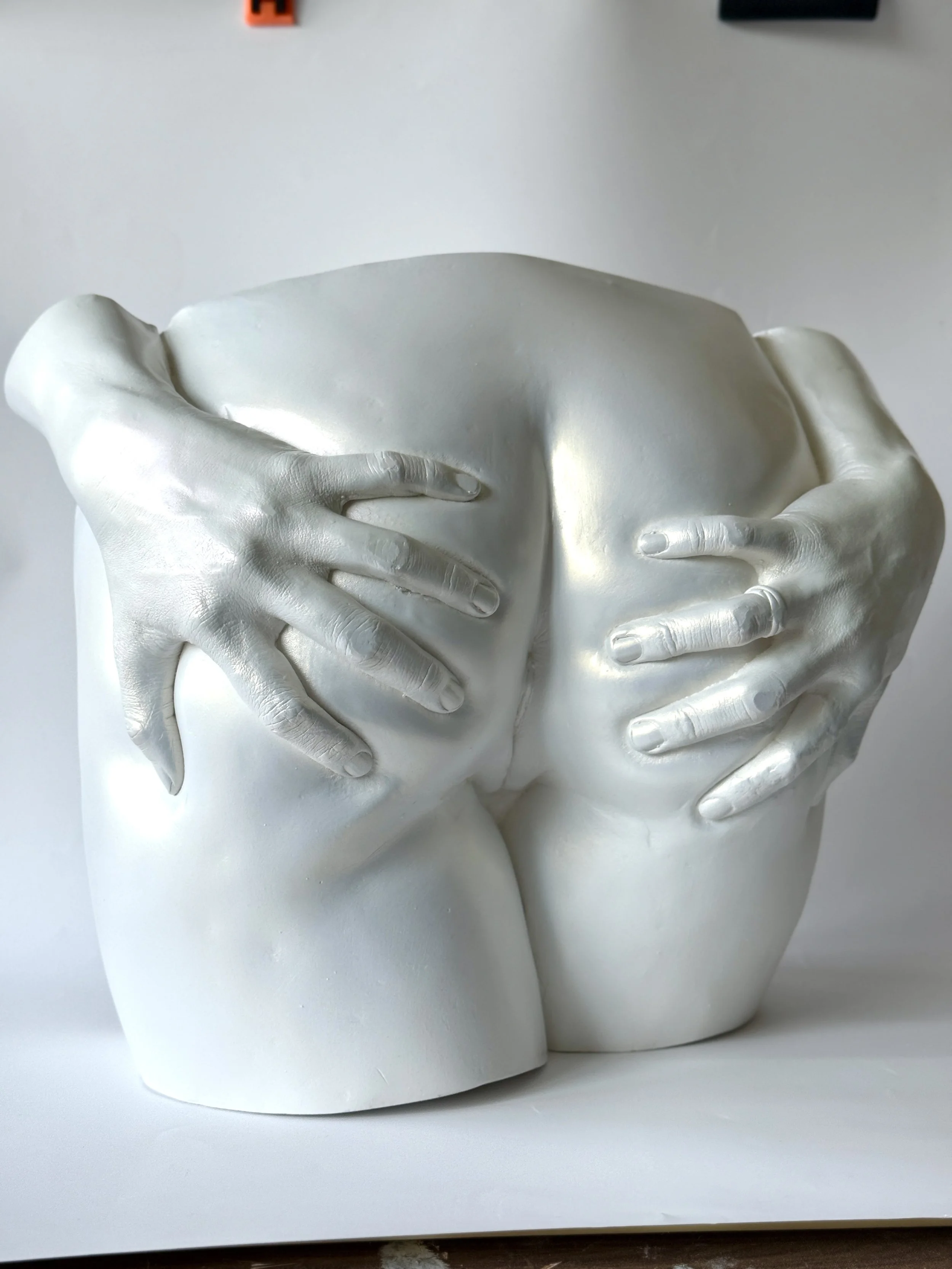 Two white mannequin heads with hands covering their faces, against a plain background.