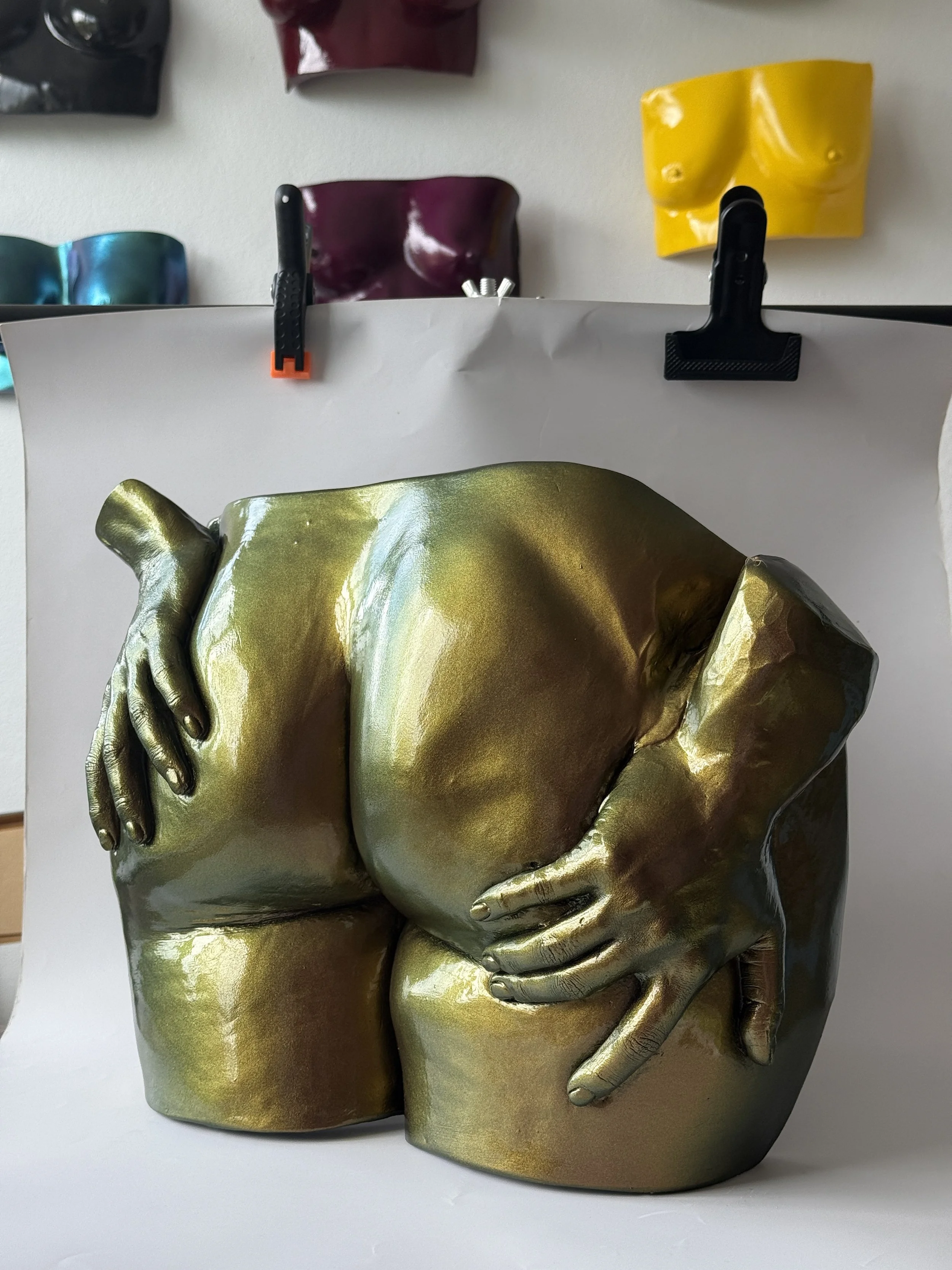 A metallic bum casting sculpture of two human hands, painted in gold color, with one hand holding the other's wrist.