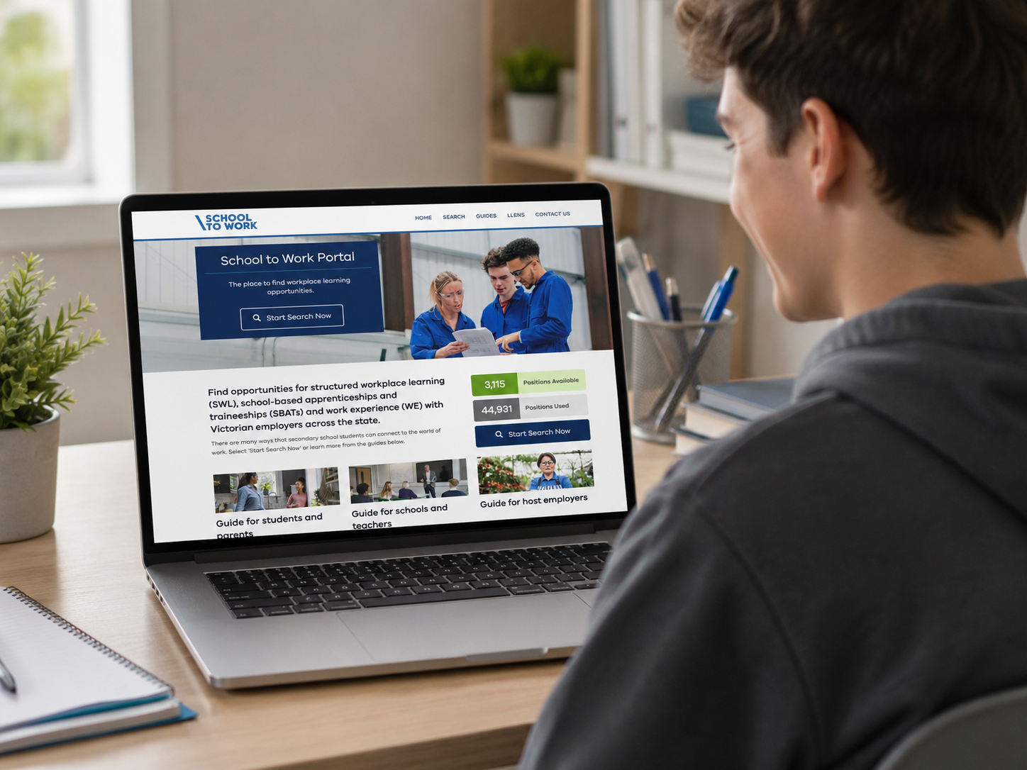 Person viewing a laptop screen displaying a website called 'School to Work' with information about workplace learning opportunities and search options on a wooden desk.