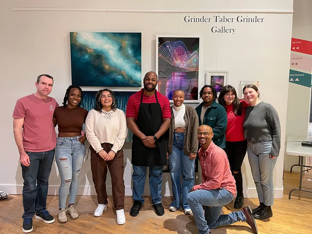 A group of ten diverse people posing together at an art gallery.