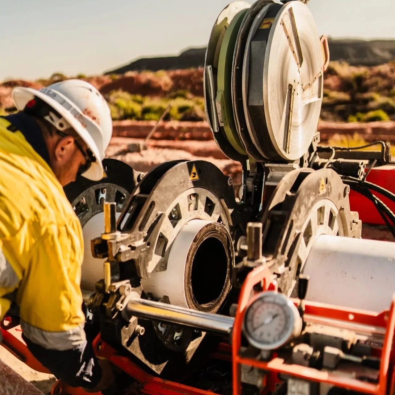 Technician performing HDPE pipe fusion welding during a mining pipeline installation project.