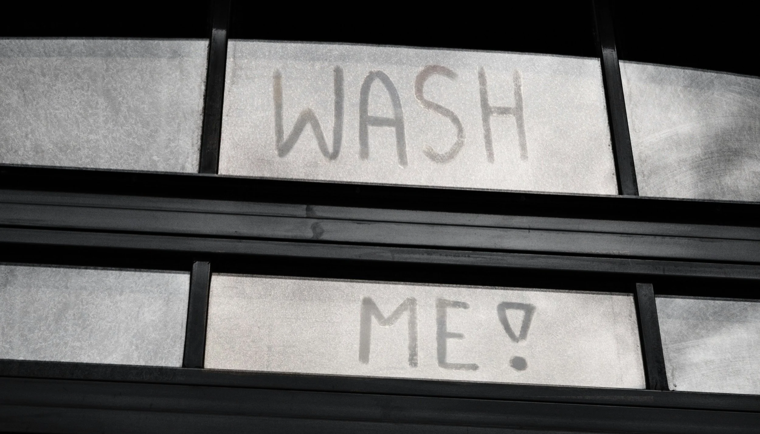 A dirty window with "wash me" written backwards
