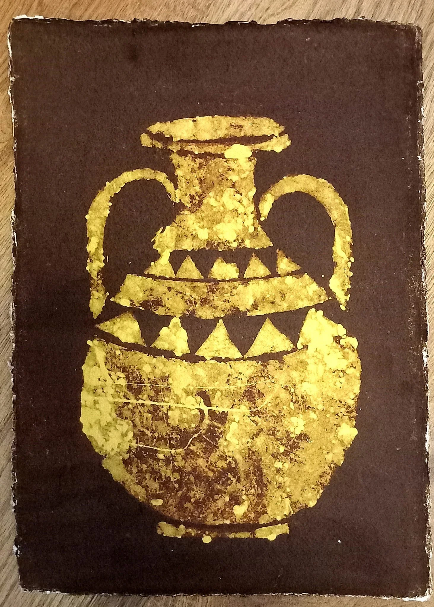 Artwork depicting an ancient vessel or urn. Gold with black background
