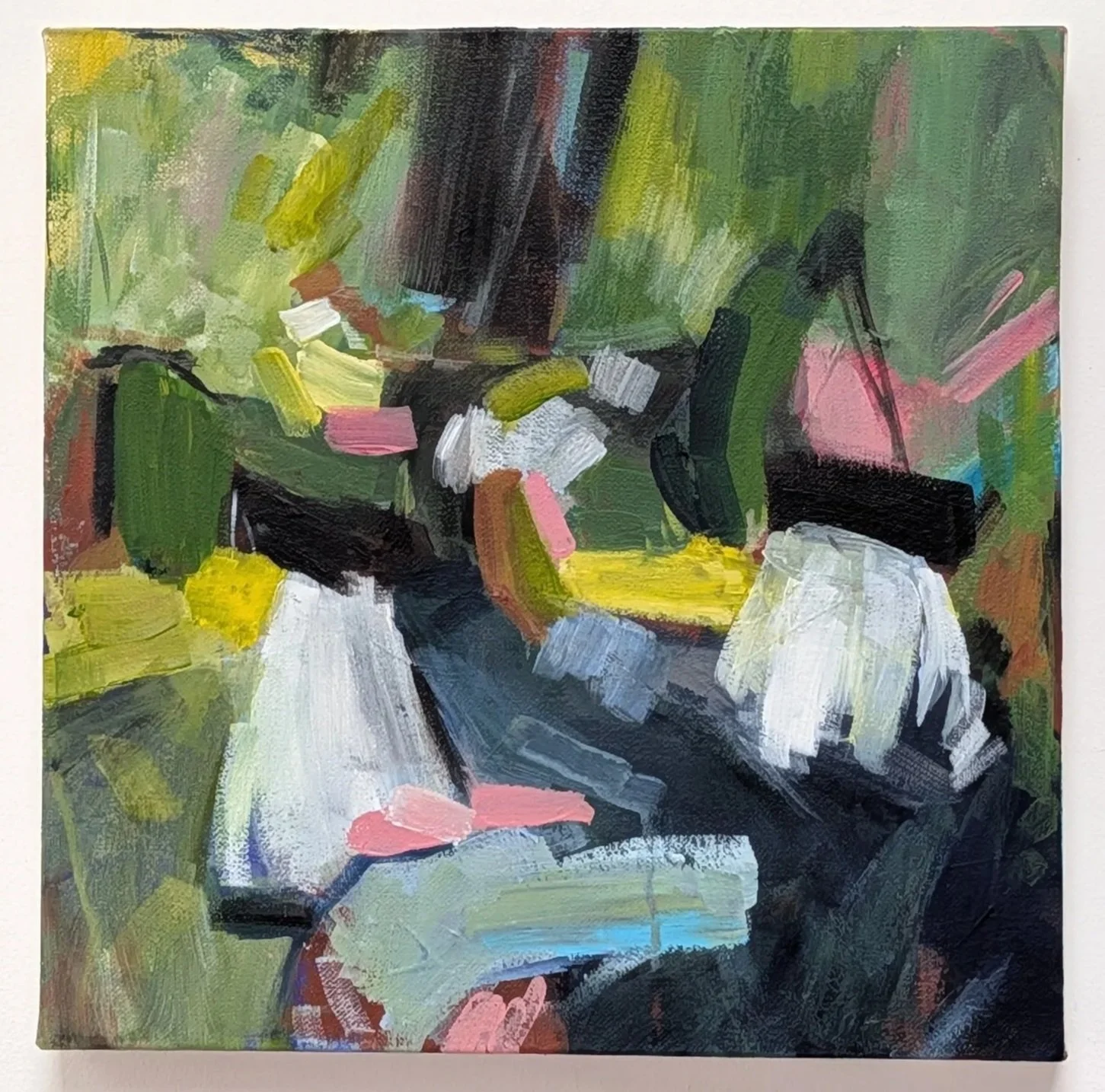 An abstract impressionist painting with bold brushstrokes in green, yellow, pink, black, white, and blue, depicting a lush landscape or scene with a table or surface in the foreground.