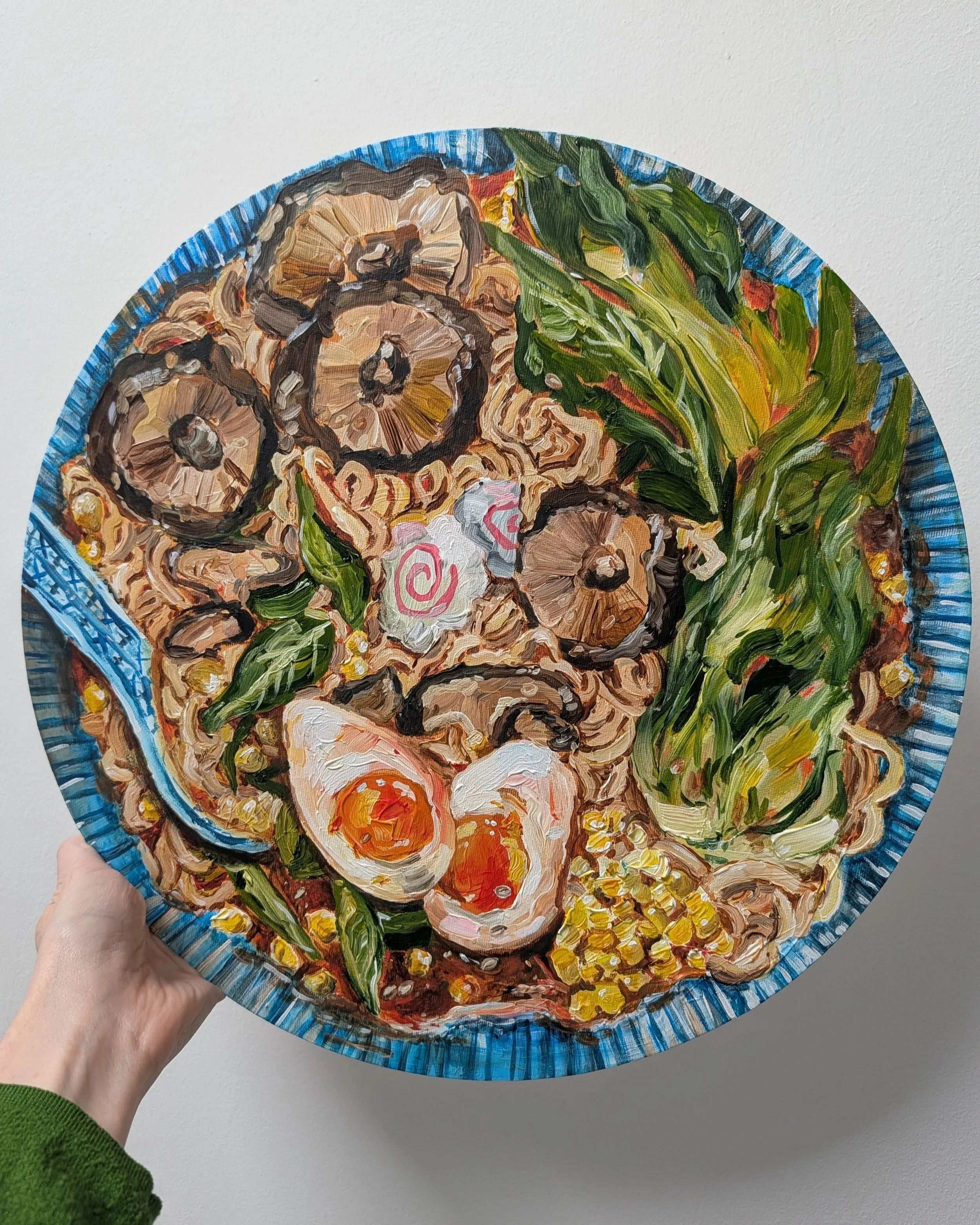 Painted decorative plate featuring a design of sliced mushrooms, leafy greens, and a narutomaki fish cake with a pink swirl, set on a white background.
