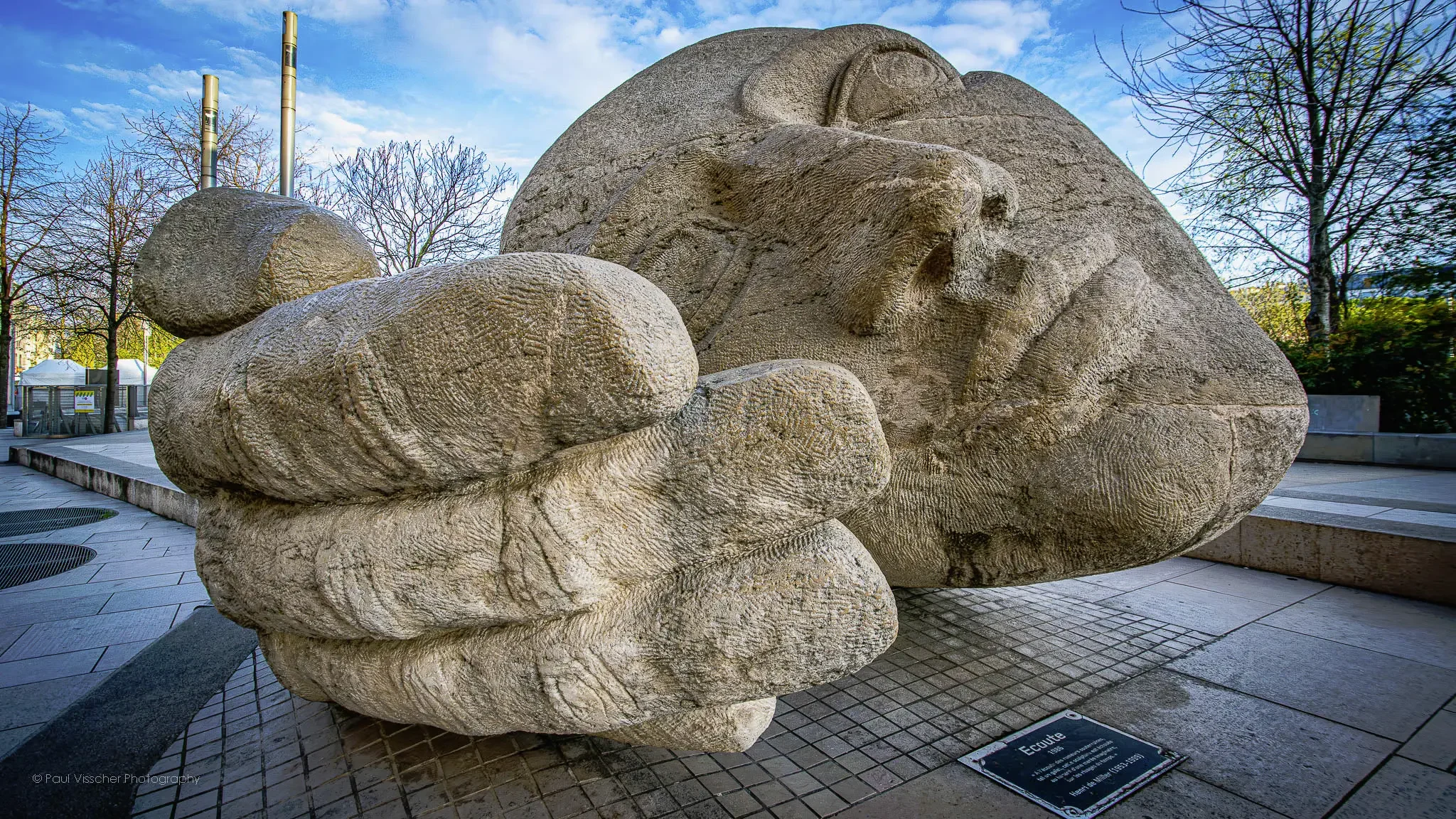 The monumental stone sculpture Écoute by Henri de Miller rests quietly in the heart of Paris, its oversized head and supporting hand creating a serene, contemplative presence in the urban plaza. Original photo by Paul Visscher Photography.