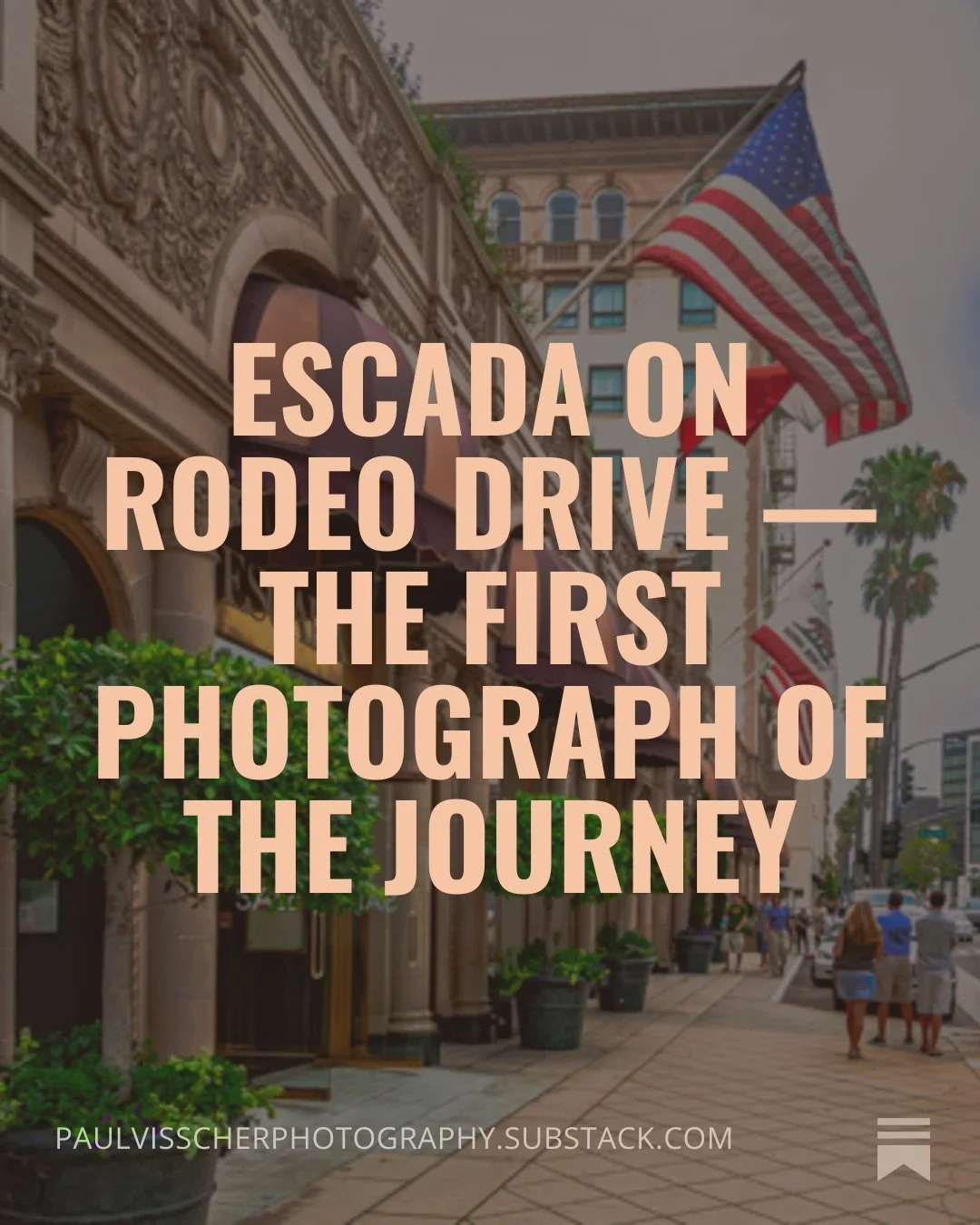 Street view of Rodeo Drive with storefronts, palm trees, and people walking, American flags hanging from buildings.