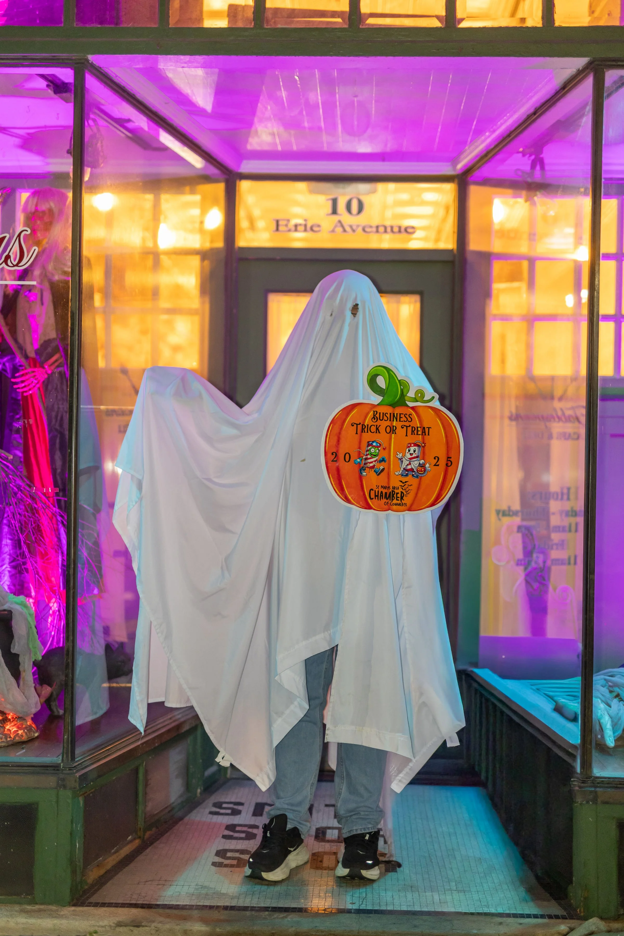 Storefront display decorated for Halloween with ghostly figure made from white sheets and sign reading 'Business Trick or Treat' with pumpkin and cartoon characters, located at 10 Eadie Avenue.
