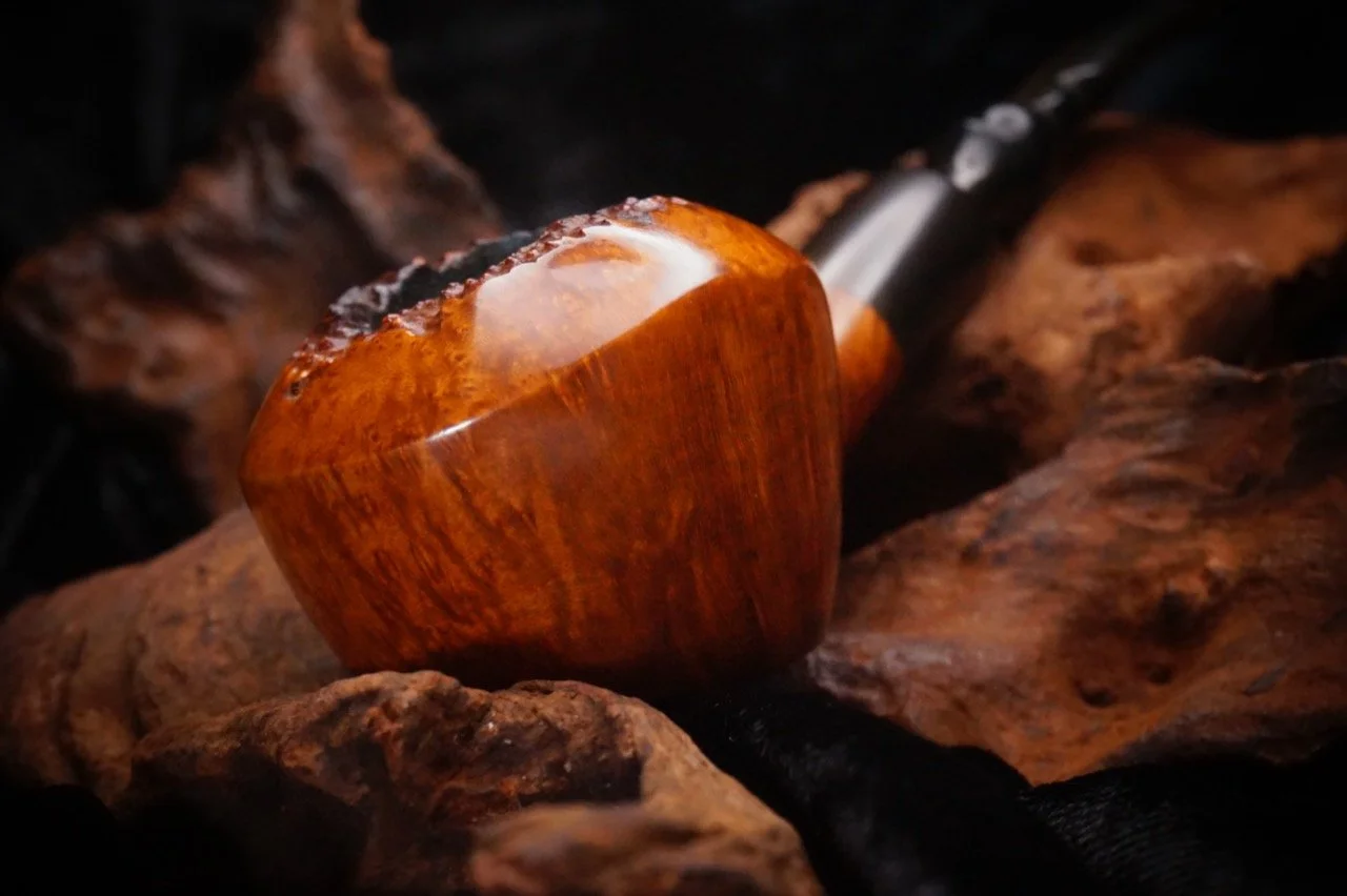 Close-up of a wooden pipe resting on a piece of wood.