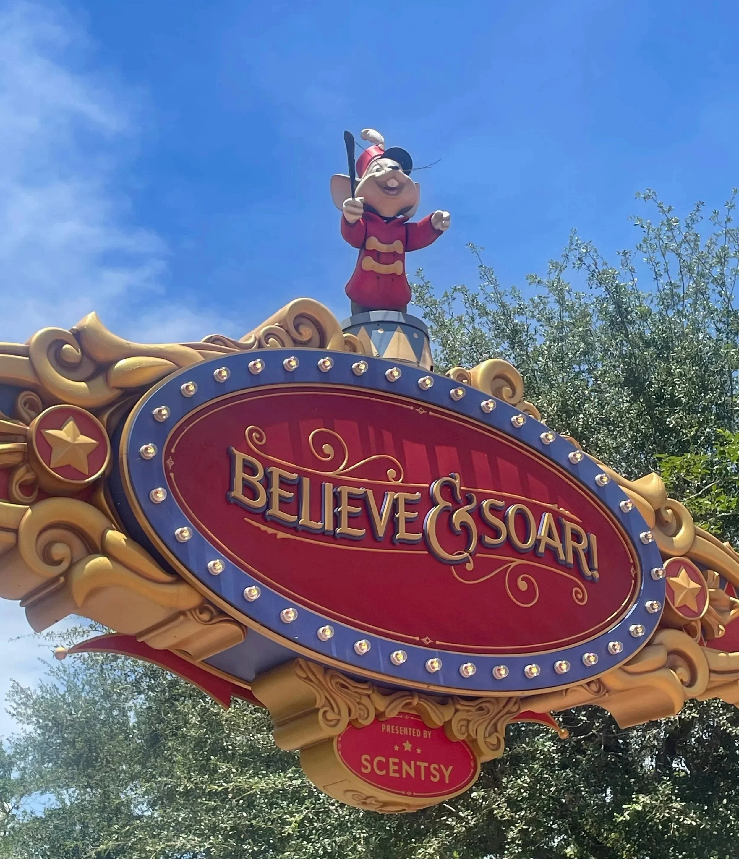 Dumbo mouse atop the Believe and Soar sign