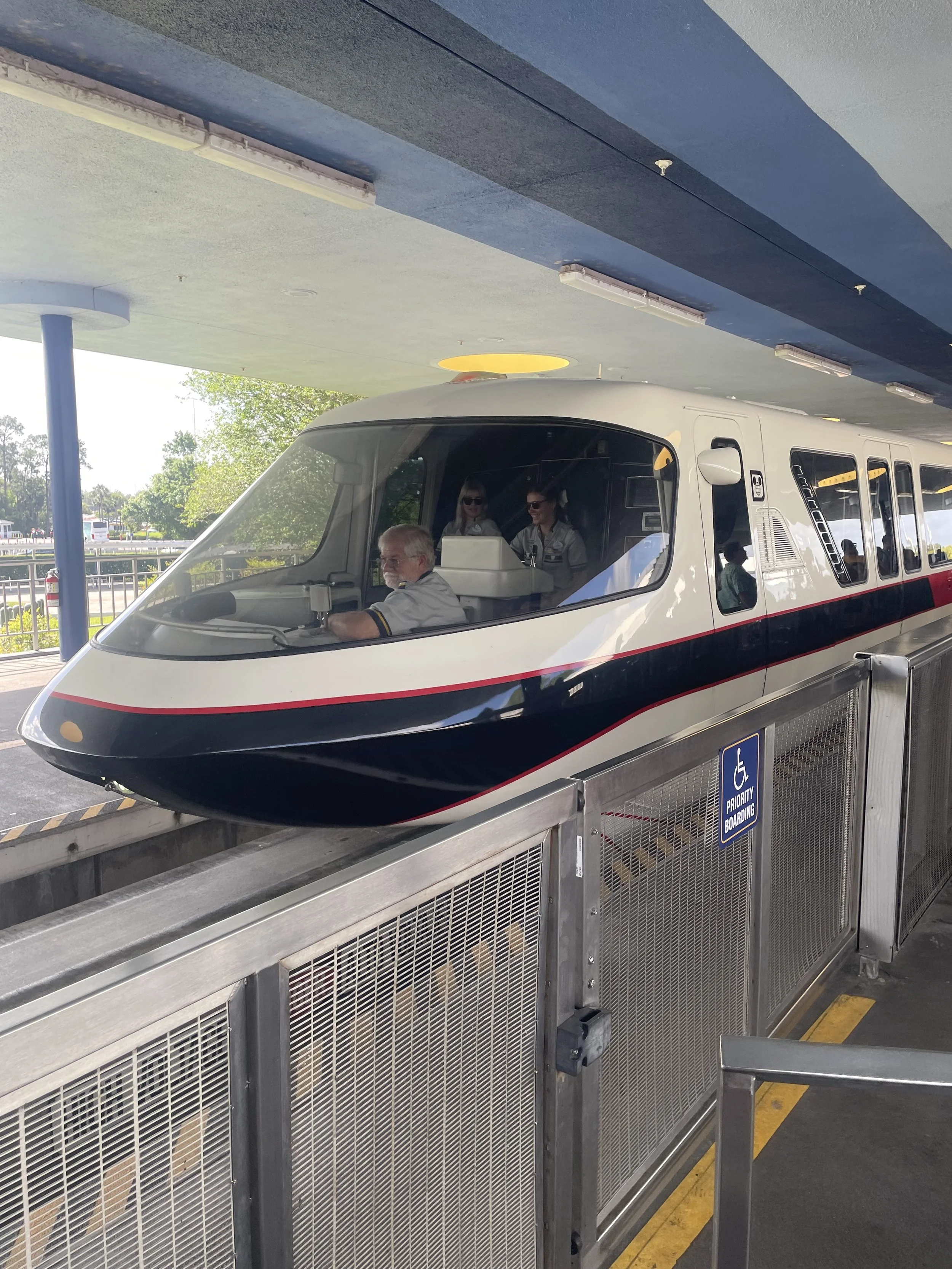 A monorail train coming into the station. Through the window are the driver and two other cast members riding in the cab.