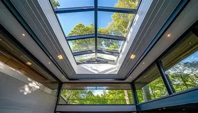 Indoor room with large glass ceiling and windows, showing trees outside.
