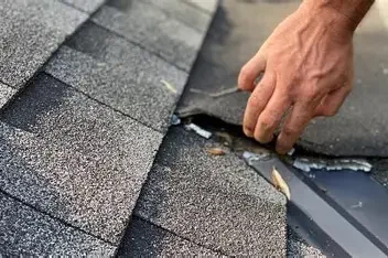 Close-up of a person's hand repairing a roof shingle.