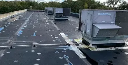 Roof with multiple HVAC units and weathered ventilation equipment.