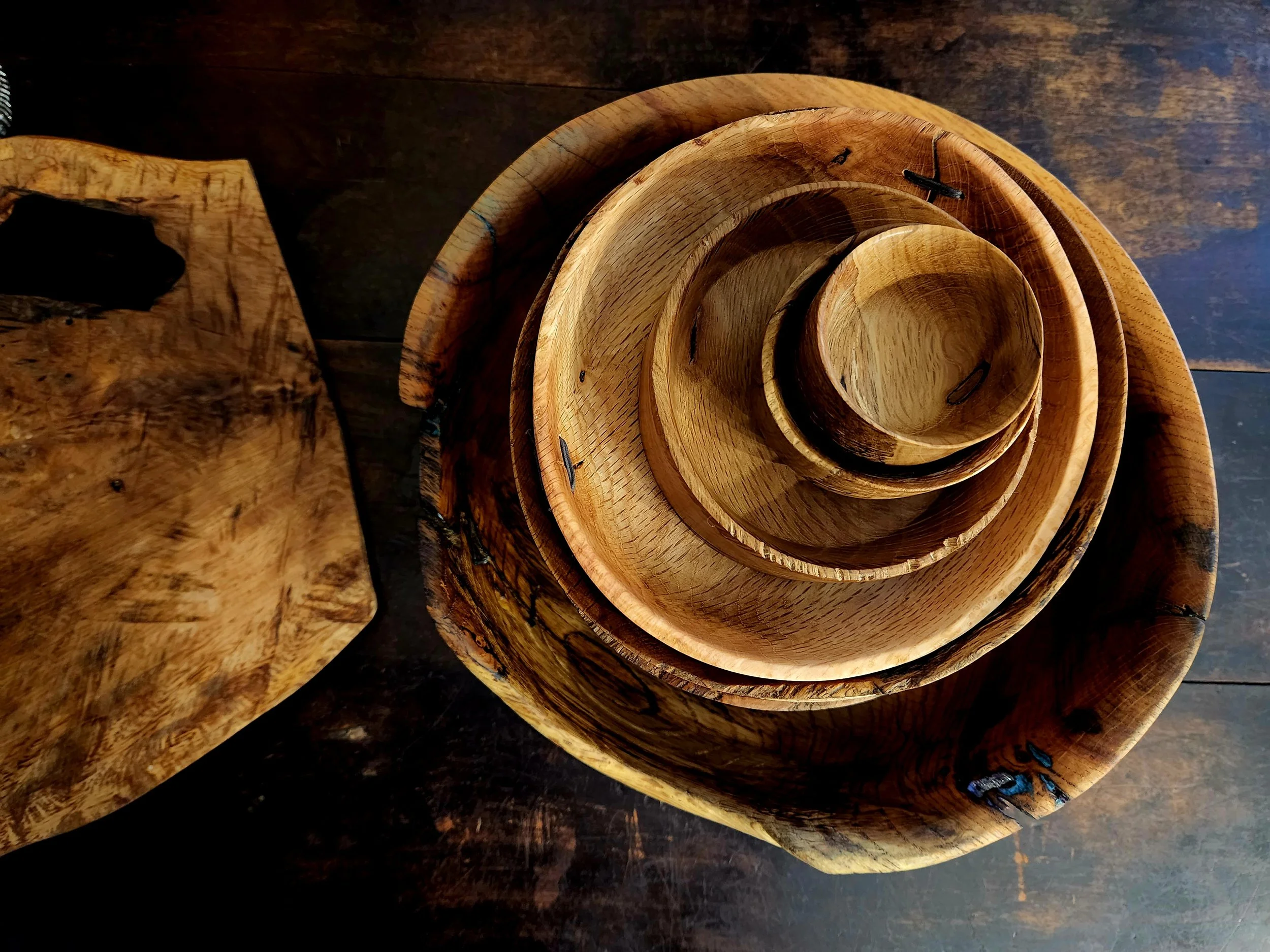 Stacked wooden bowls of varying sizes on a dark wooden surface.