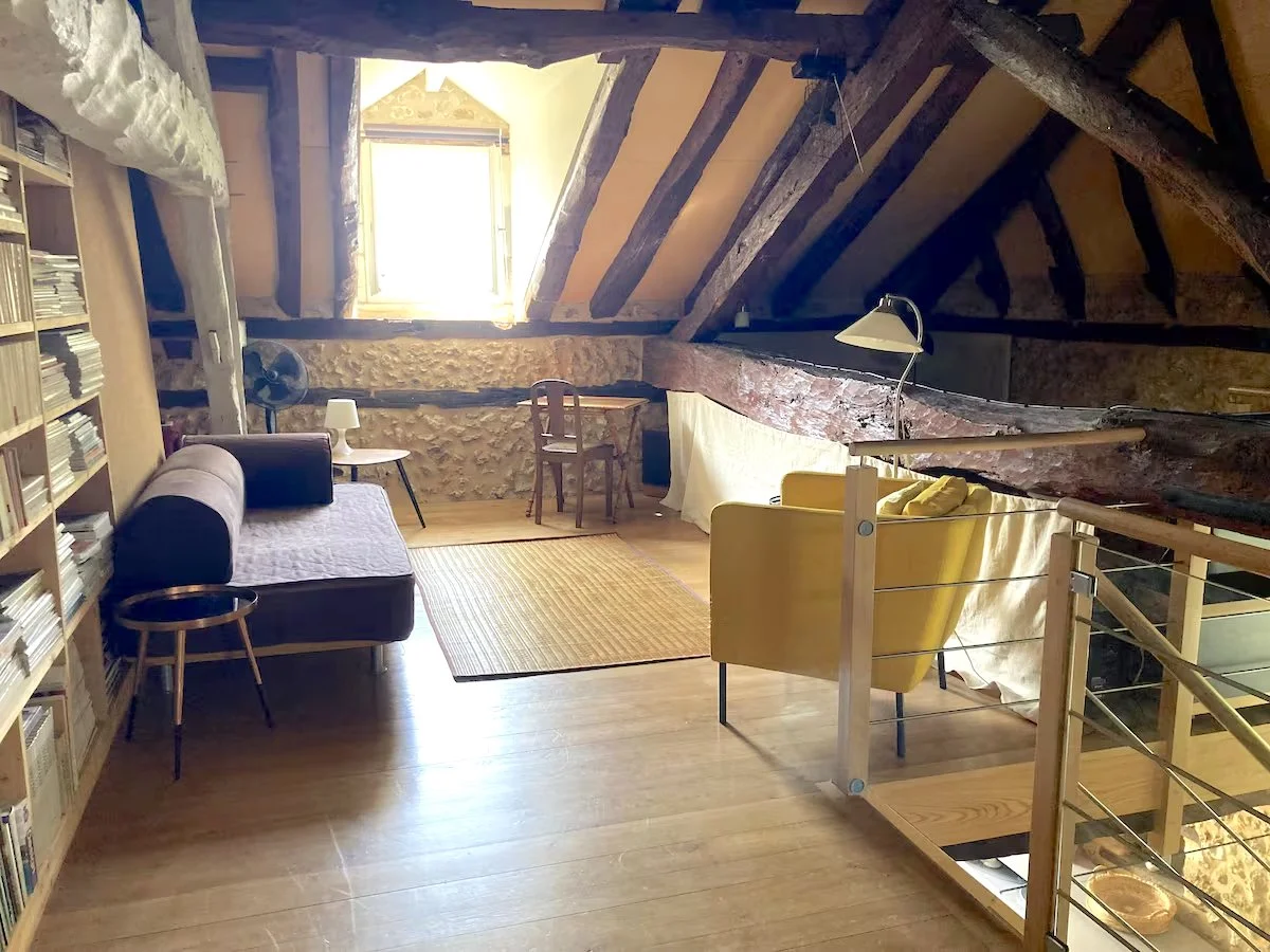 L'espace mezzanine avec bibliothèque, canapé, chaise jaune, bureau