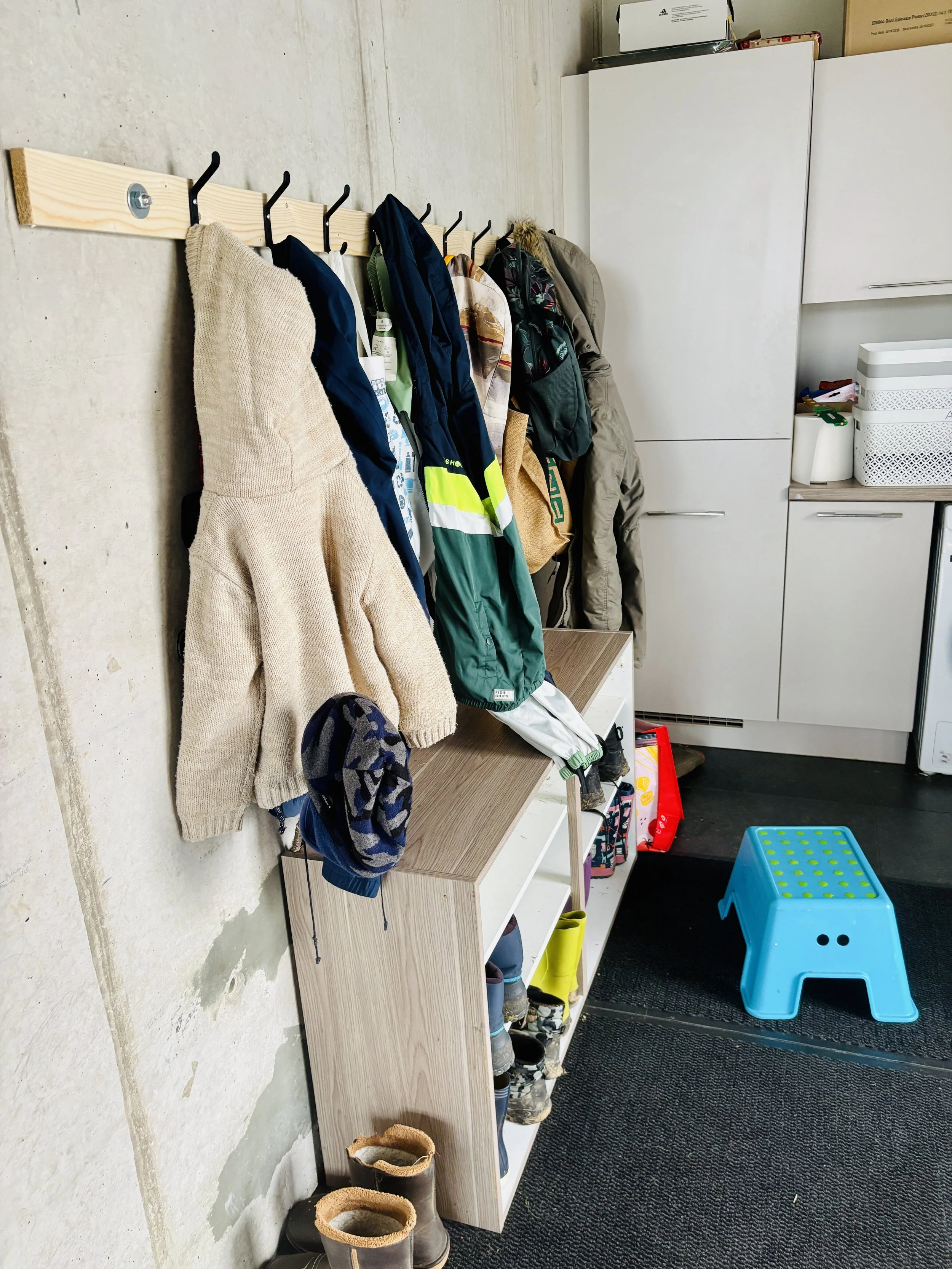 Chaussures et bottes de pluie salees rangées sur une étagère en bois.