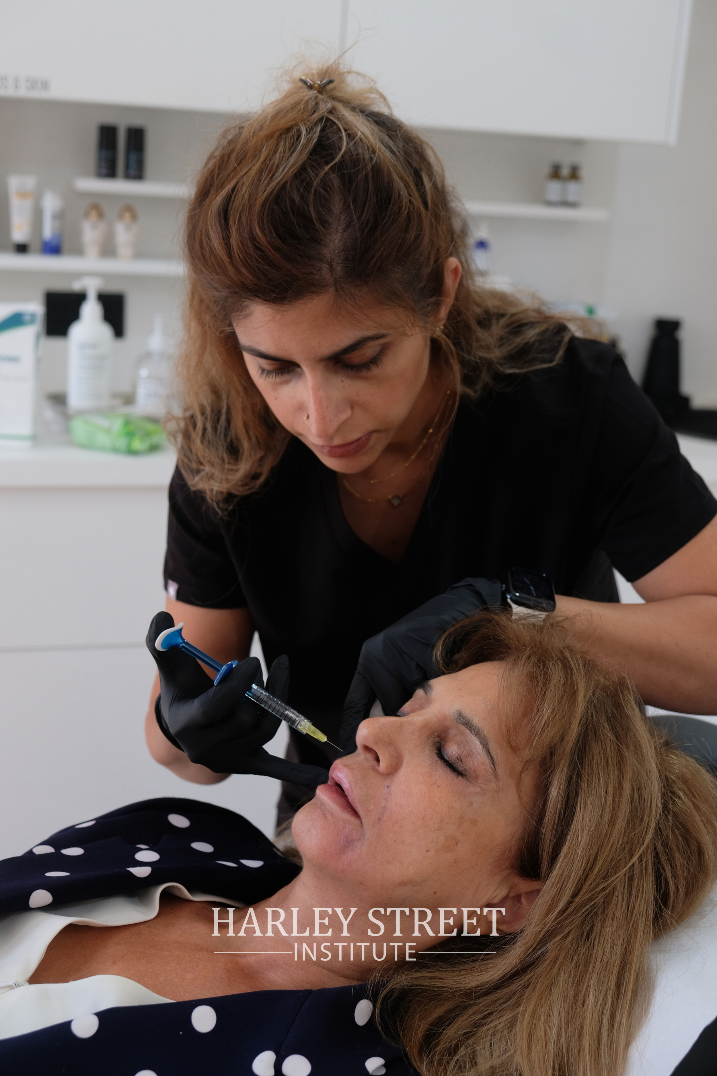 A medical professional wearing black gloves administering an injection to a client's cheek for polynucleotides treatment
