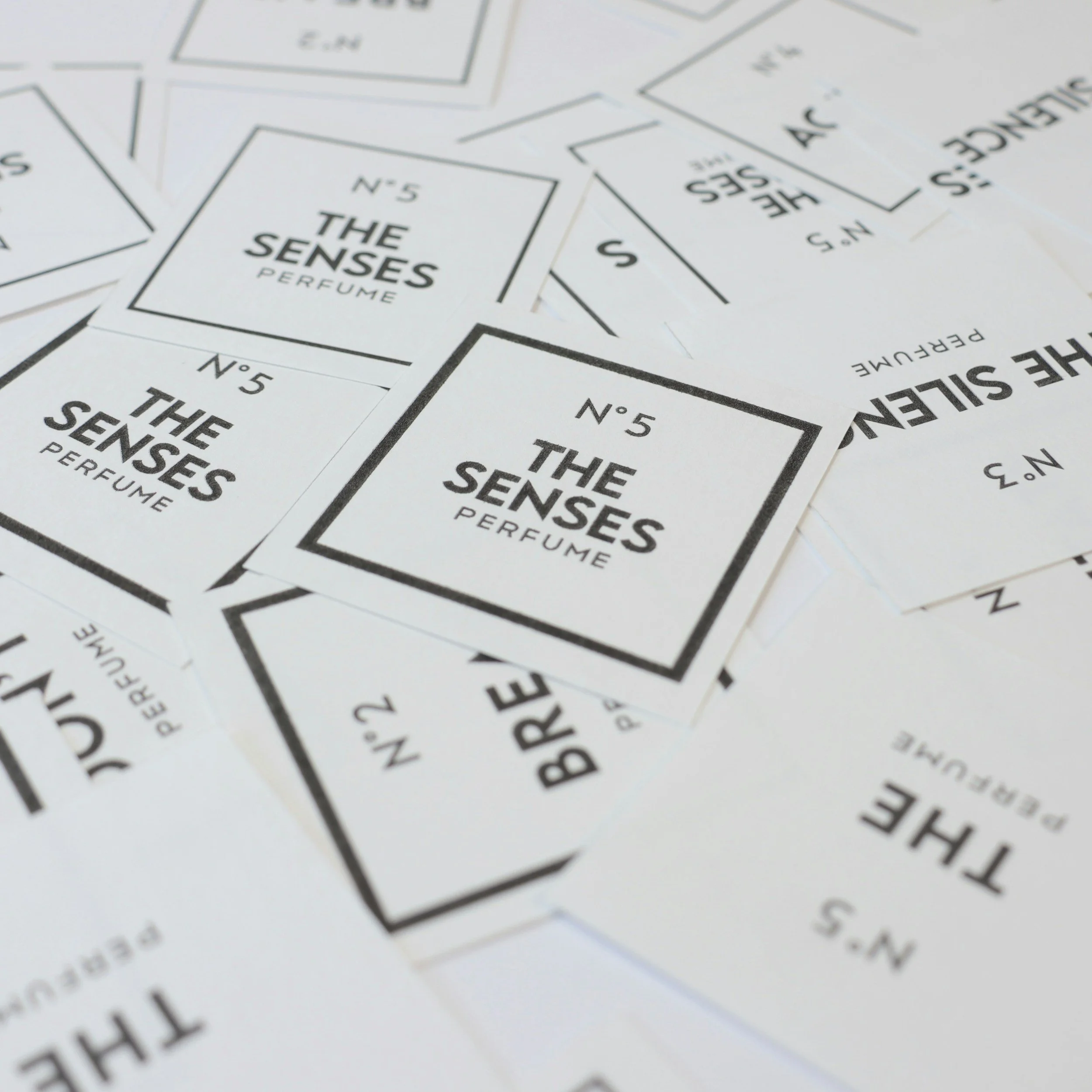 Multiple small white packets with black borders and text that reads "The Senses" and "Perfume."