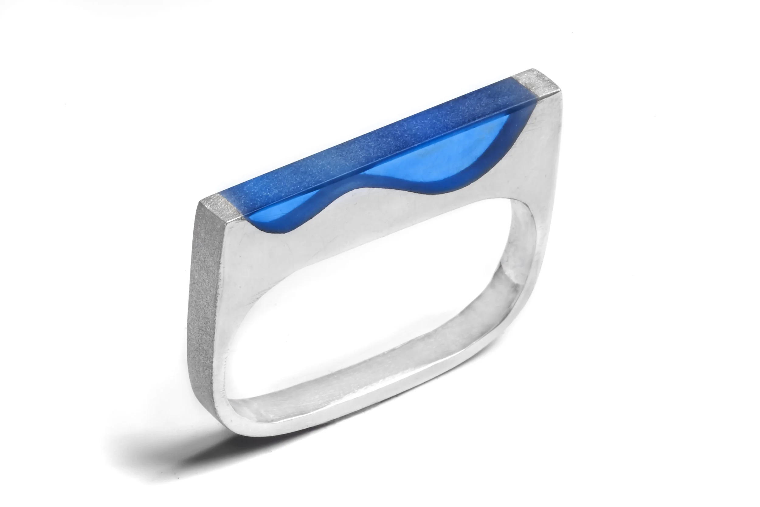 A silver ring with a blue wave-shaped inlay on a white background.