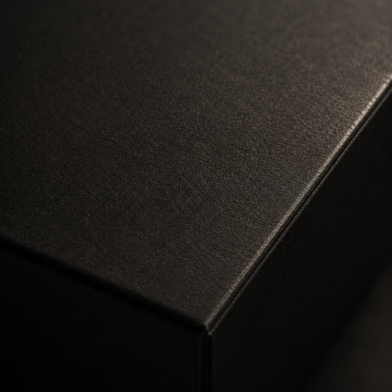 Detalle de superficie texturizada negra con iluminación editorial y acabado mate.