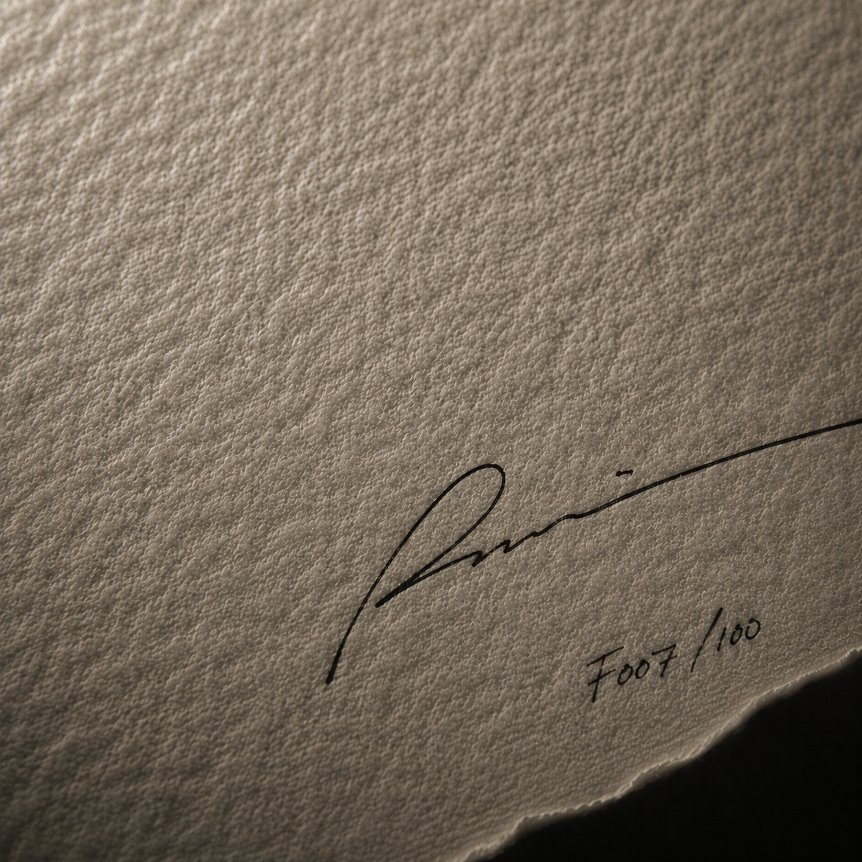 Firma manuscrita sobre papel texturizado con numeración limitada, reflejando artesanía y exclusividad editorial.