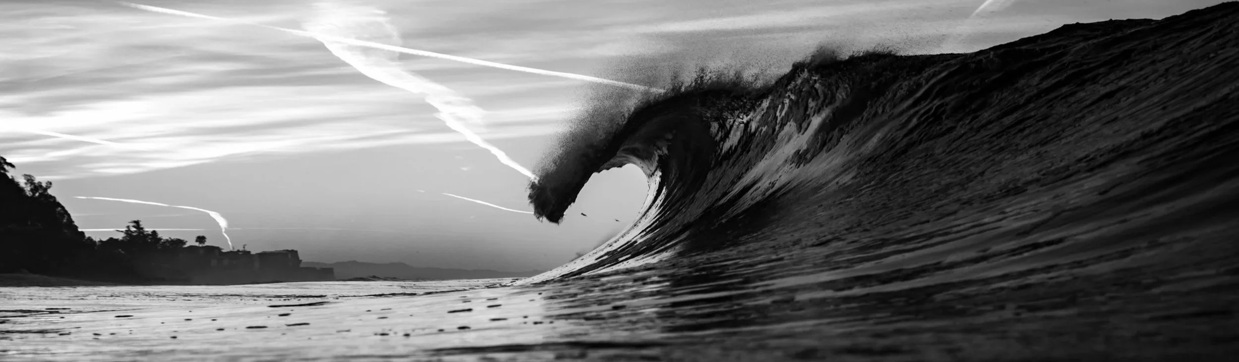 Black and white photograph of a large ocean wave curling.