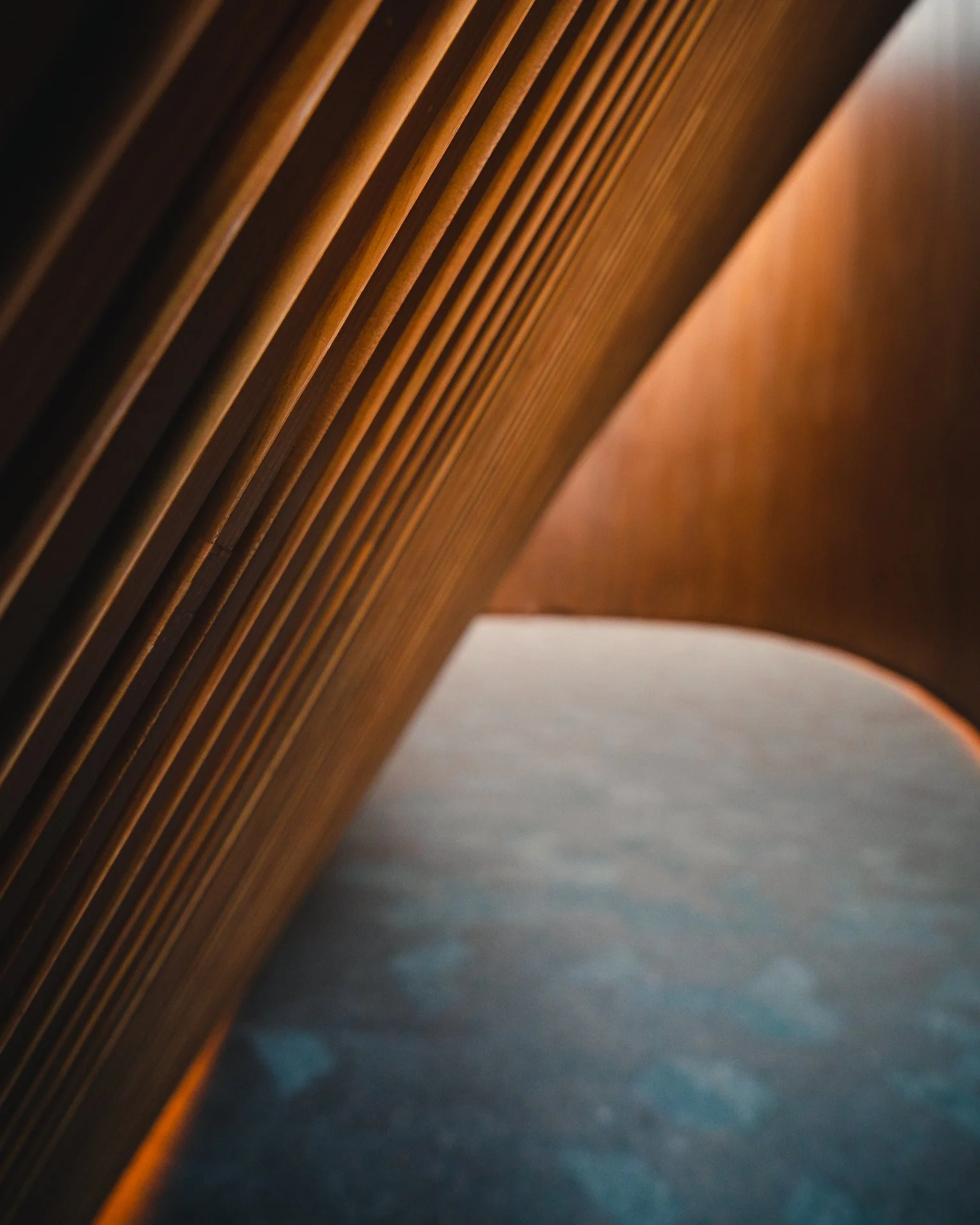 Une photo prise à un angle oblique montrant une surface en bois avec des lattes parallèles et une surface en pierre ou en béton en dessous.
