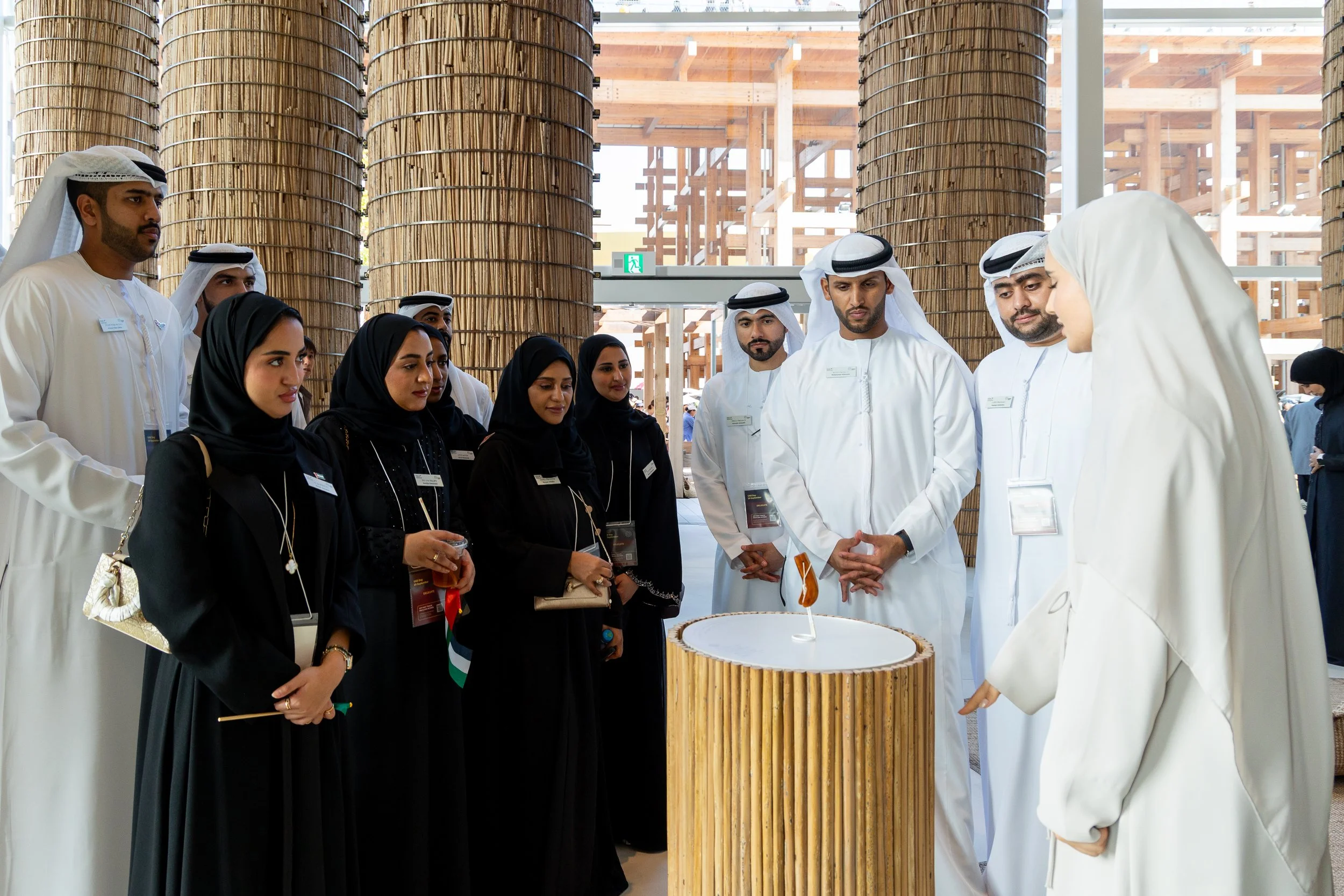 Groupe de personnes avec des hommes en vêtements traditionnels arabes et des femmes en vêtements noirs, lors d'une visite ou d'une exposition.