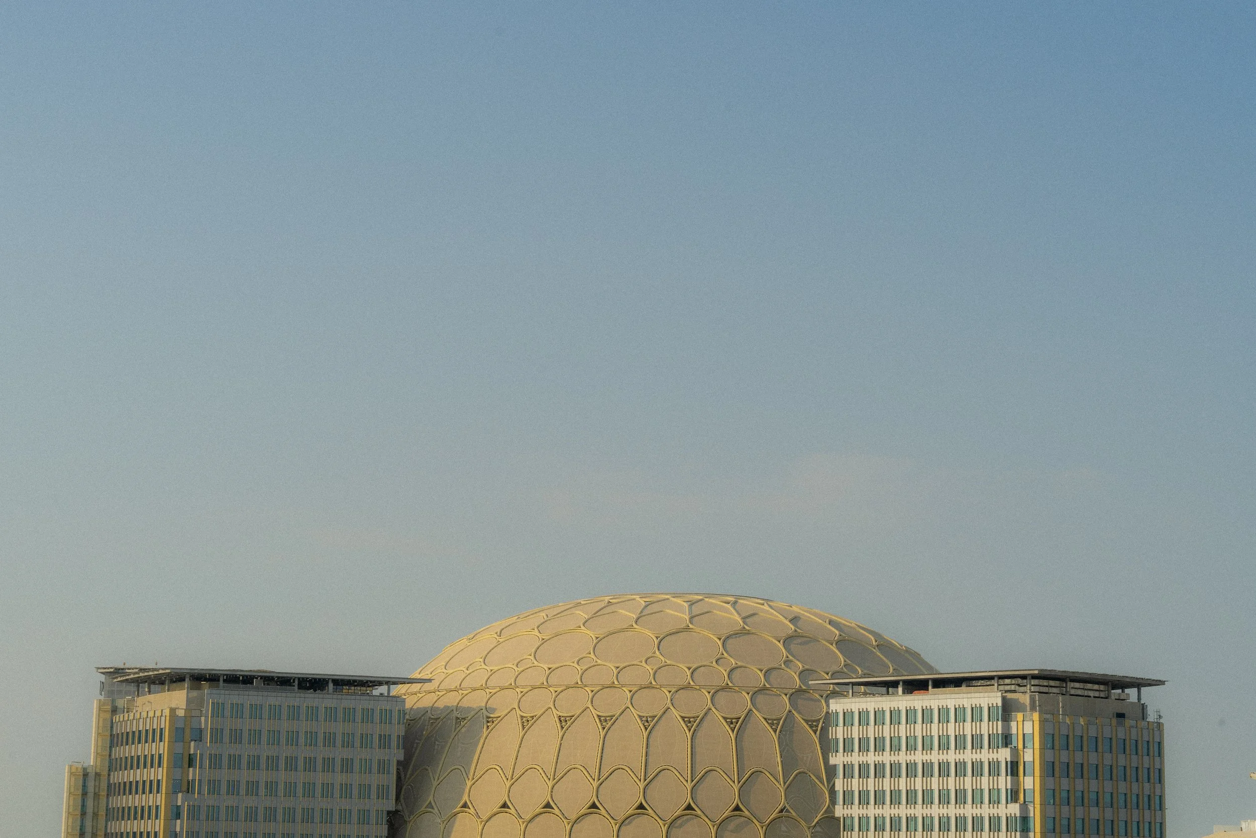 Photo d'un bâtiment moderne avec une grande coupole dorée sous un ciel clair, probablement lors de la journée.