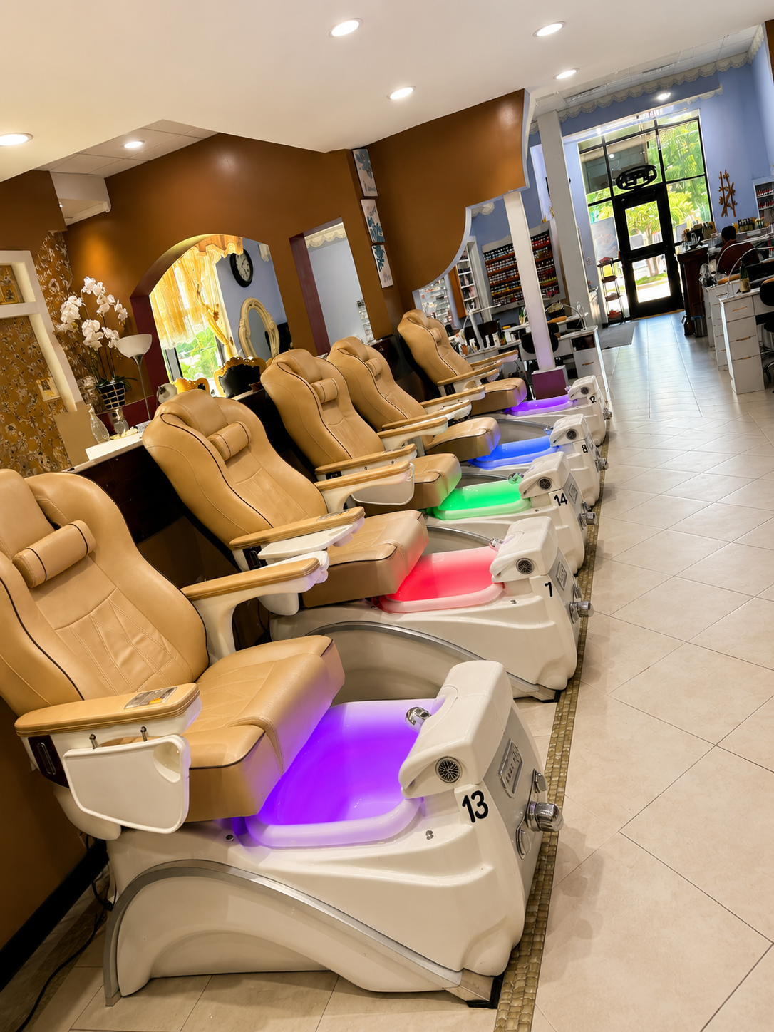Pedicure chairs with illuminated foot basins in a nail salon.