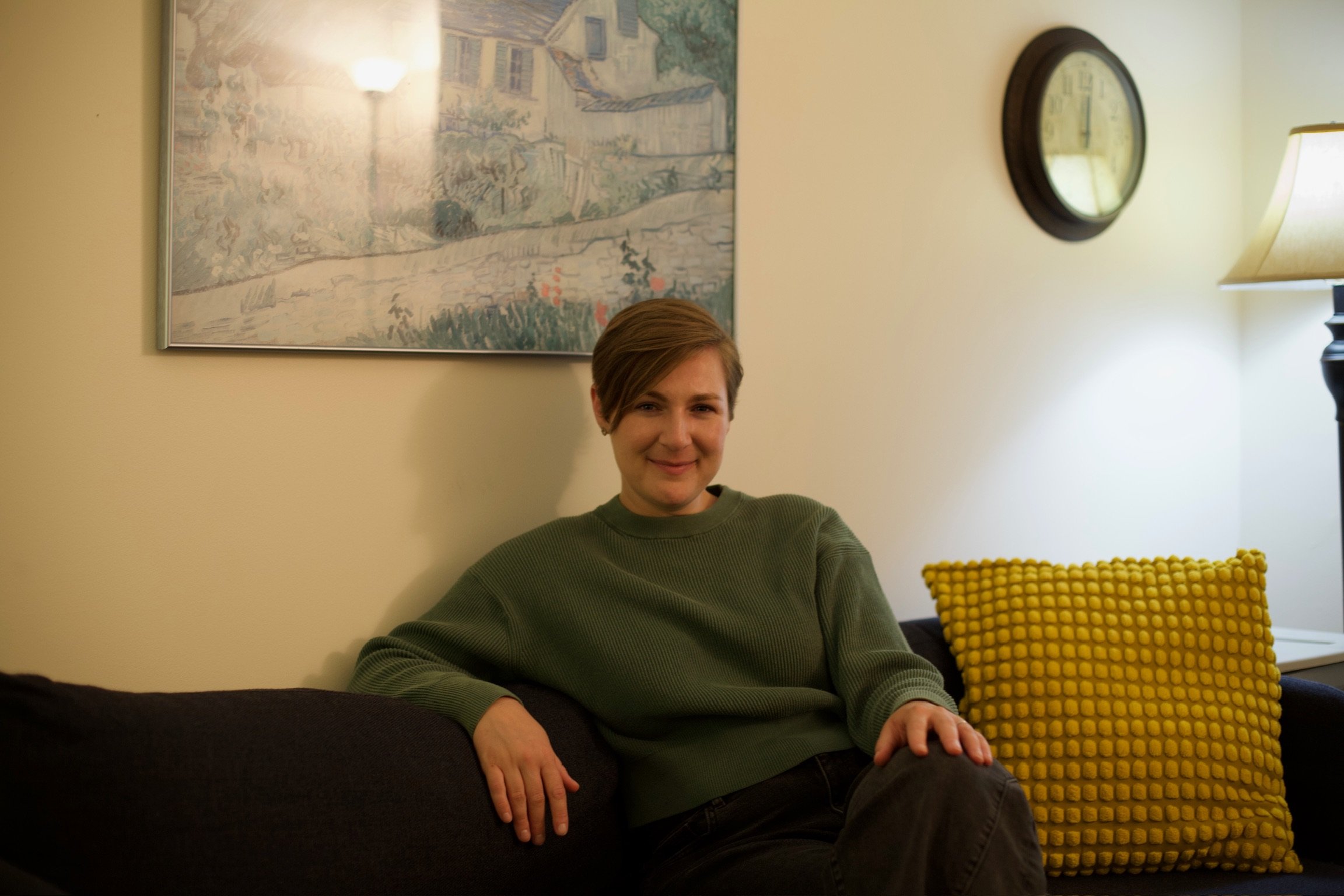 a photo of Leya smiling, sitting on the blue couch in her office
